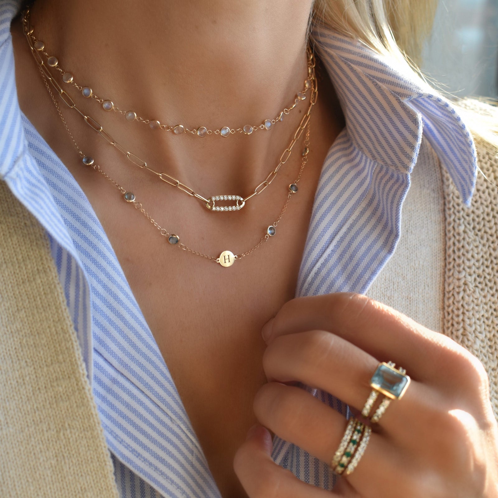 Woman wearing multiple necklaces including a gold Adelaide paperclip chain pavé necklace featuring a gemstone-encrusted link