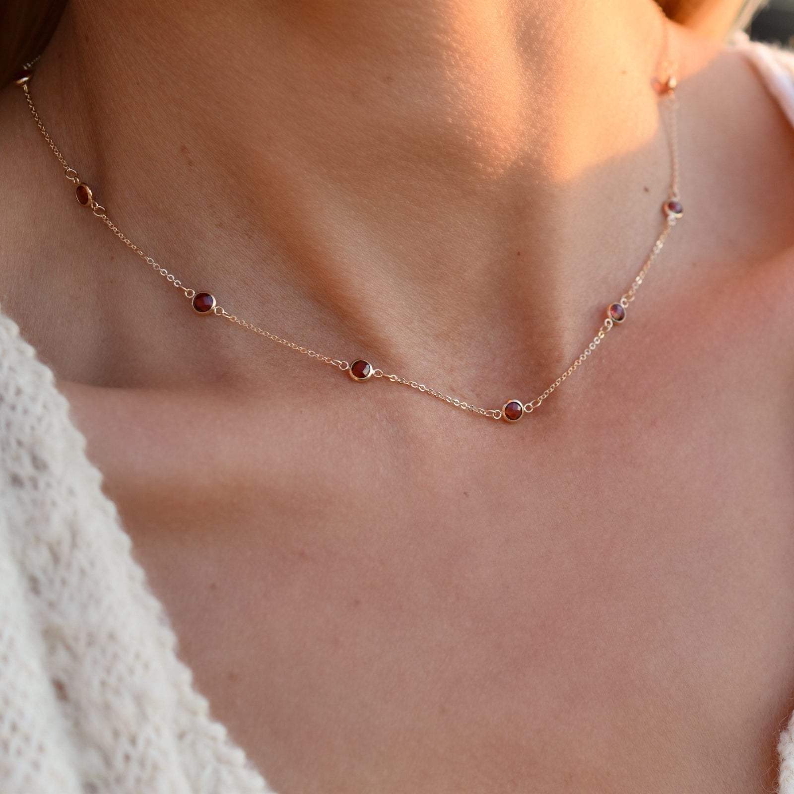 Woman wearing a Bayberry 11 Birthstone necklace featuring 4 mm briolette garnets bezel set in 14k yellow gold