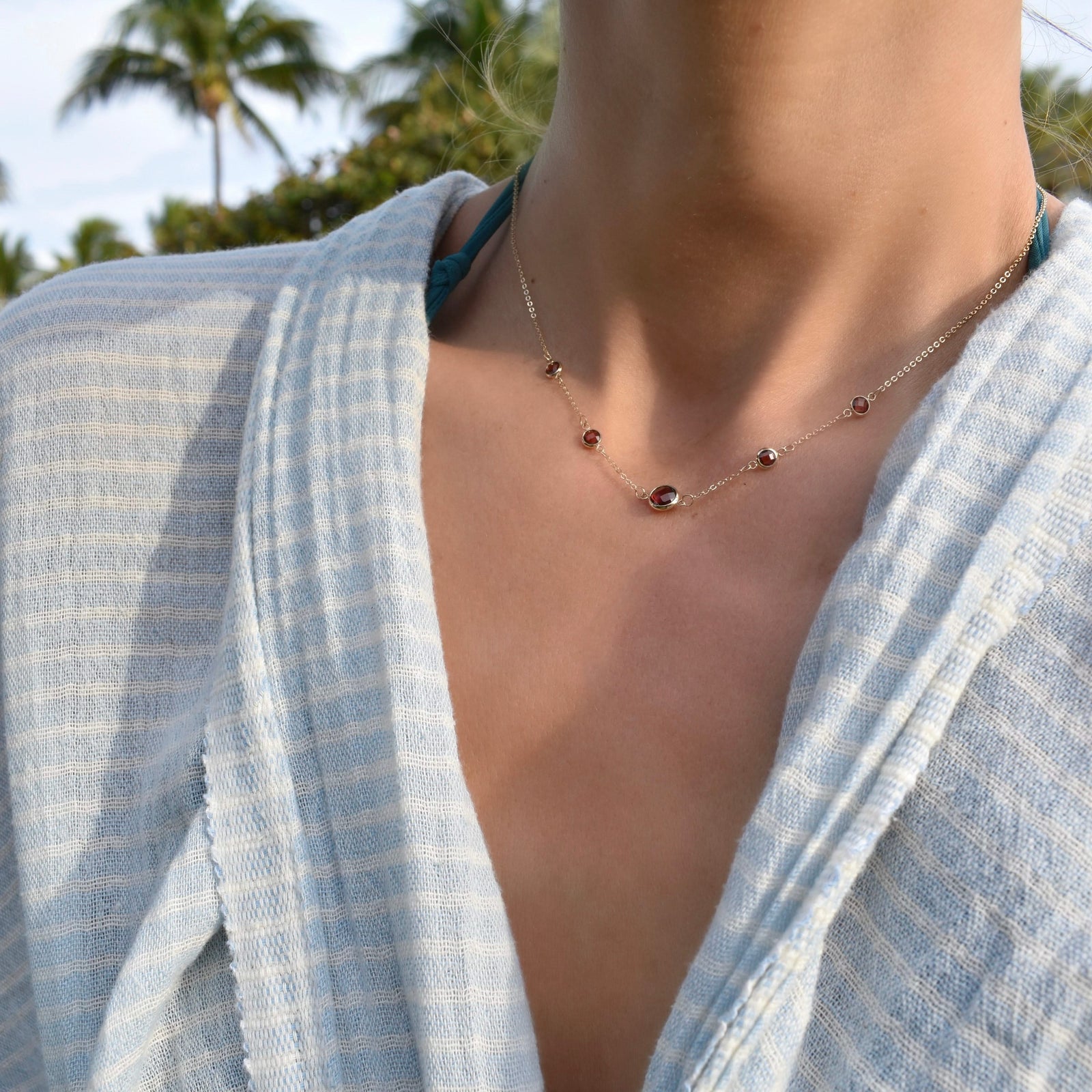 Woman with a Grand & Classic necklace featuring one 6 mm and four 4 mm Garnets bezel set in 14k yellow gold