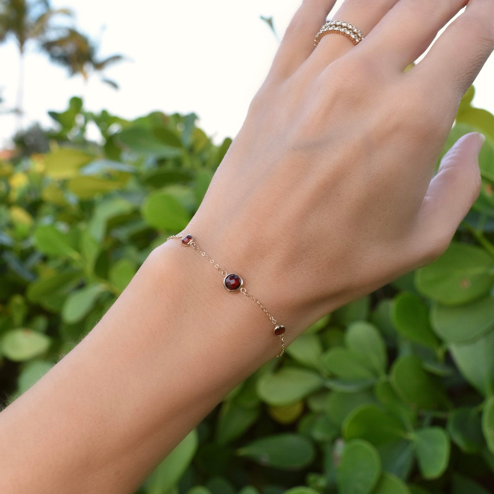 Woman wearing a Grand & Classic bracelet featuring one 6 mm and four 4 mm briolette Garnets bezel set in 14k yellow gold