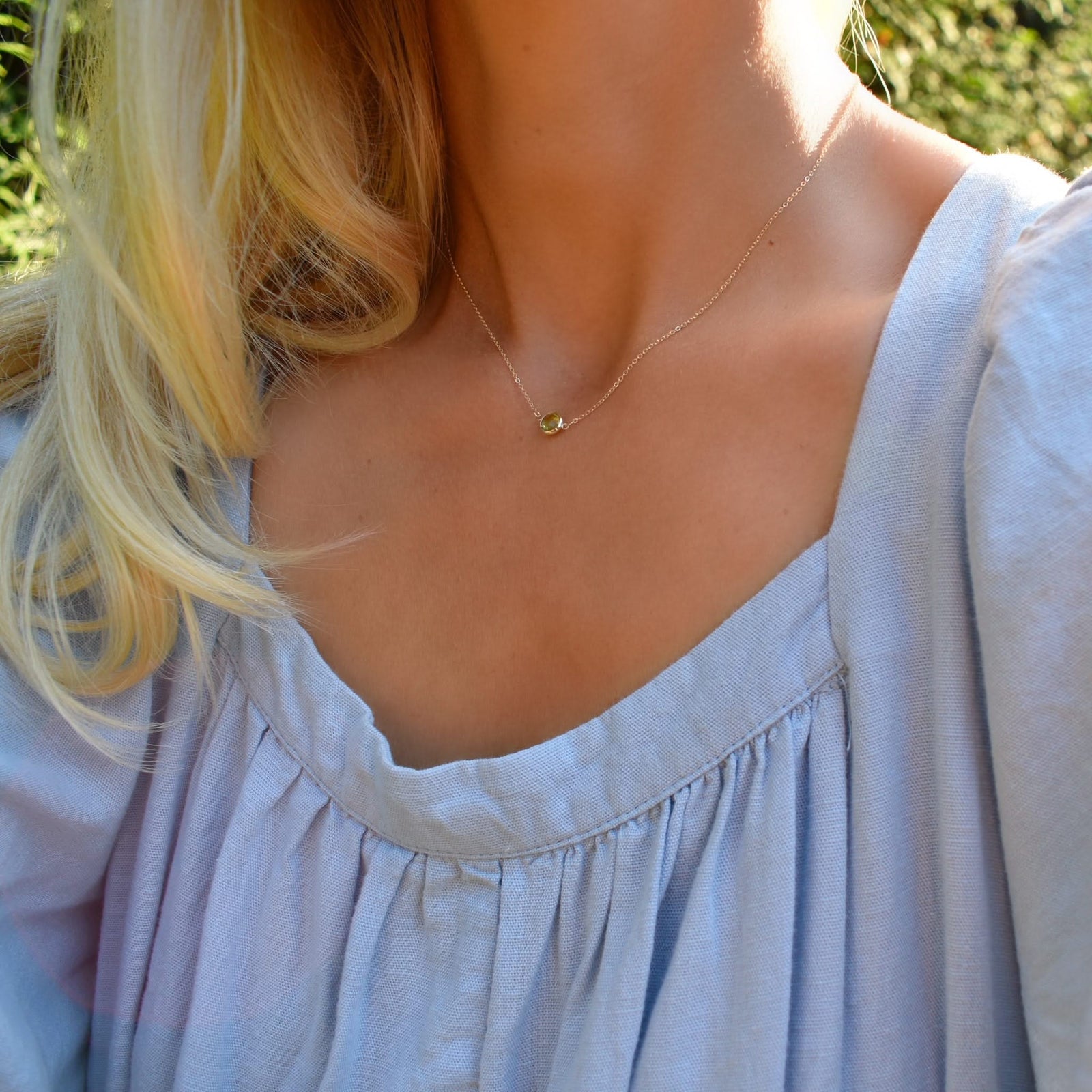 Woman wearing a Grand 14k yellow gold 1.17 mm cable chain necklace featuring one 6 mm briolette cut bezel set peridot