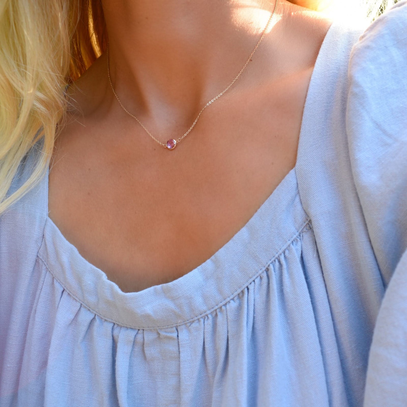 Woman wearing a Grand 14k yellow gold 1.17 mm cable chain necklace featuring one 6 mm briolette cut bezel set pink sapphire