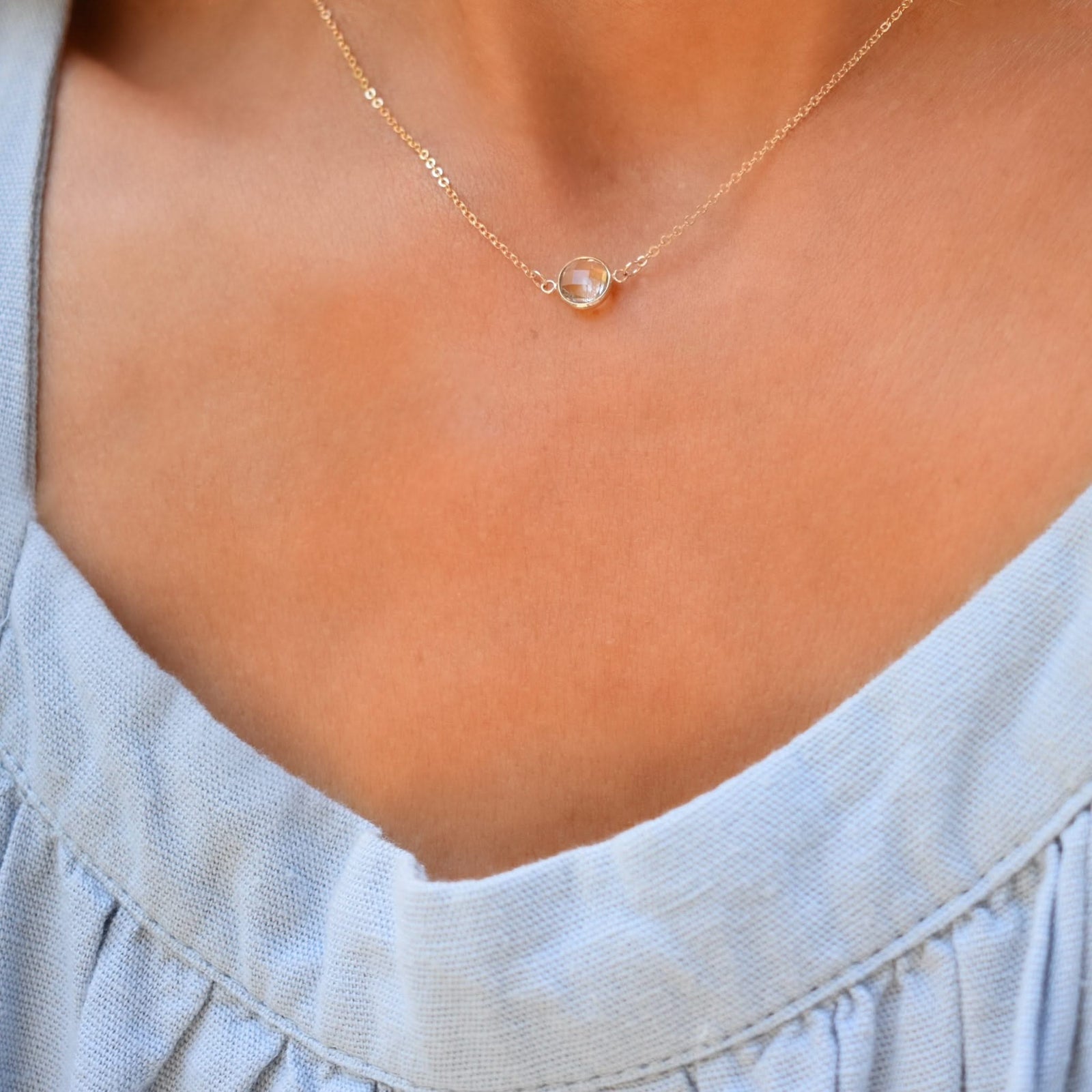 Woman with a Grand 14k yellow gold 1.17 mm cable chain necklace featuring one 6 mm briolette cut bezel set white topaz