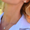 Woman wearing a necklace and a 14k gold Greenwich 4 Birthstone earring featuring four 4 mm white topaz and one 2.1 mm diamond