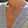 Woman wearing a Greenwich necklace featuring five 4 mm emeralds and one 2.1 mm diamond bezel set in 14k yellow gold