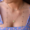 Woman wearing layered gold necklaces including a Greenwich necklace featuring five 4 mm peridots and one 2.1 mm diamond
