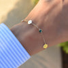 Woman with a 14k gold Classic bracelet featuring two birthstones and two 1/4” flat discs engraved with letters H & L