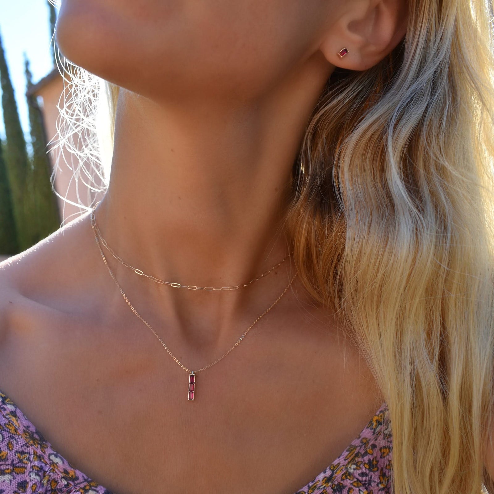 Woman wearing a Providence Ruby vertical bar pendant featuring 3 petite baguette stones set in 14k yellow gold