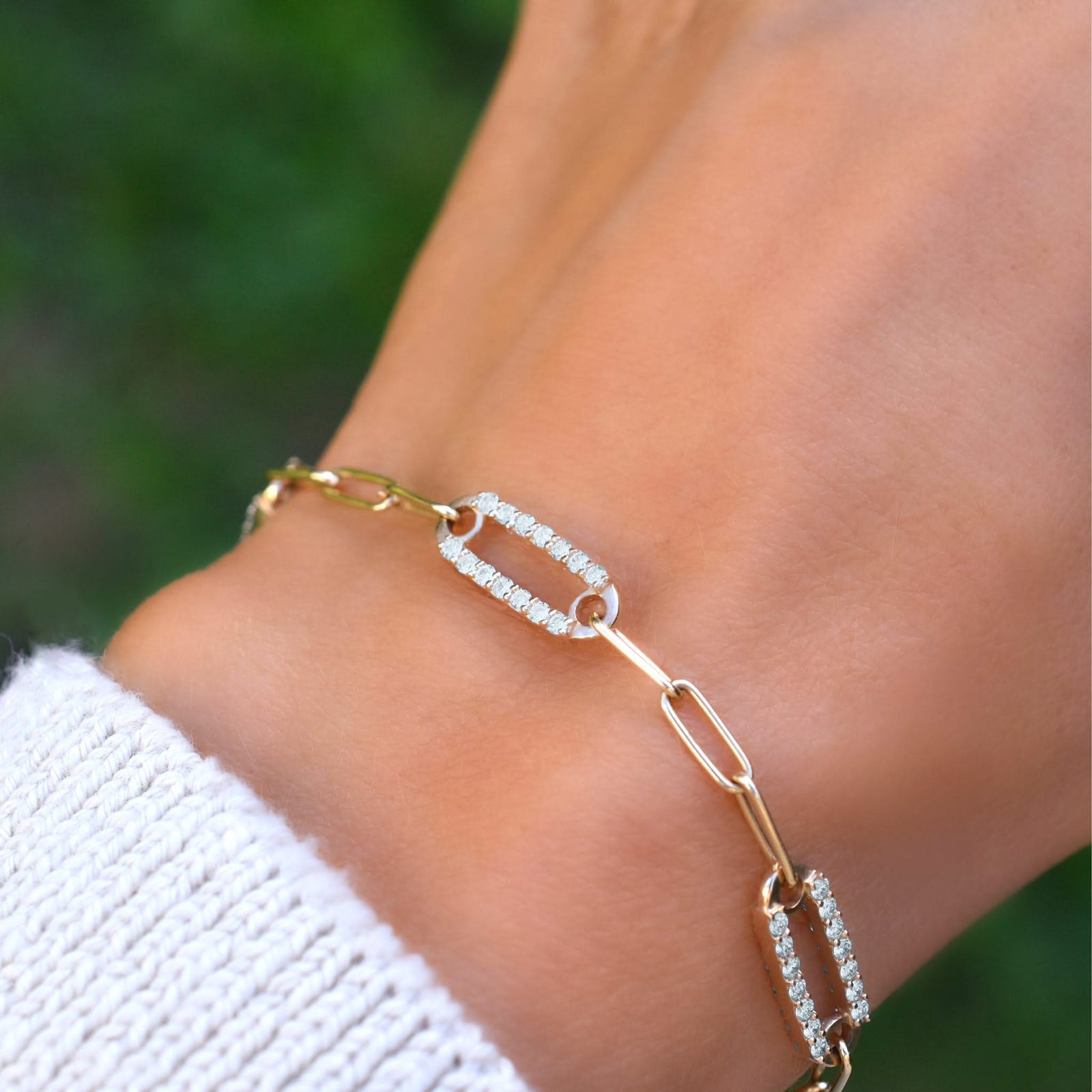 Woman wearing a 14k yellow gold Adelaide paperclip chain pavé bracelet featuring aquamarine-encrusted links