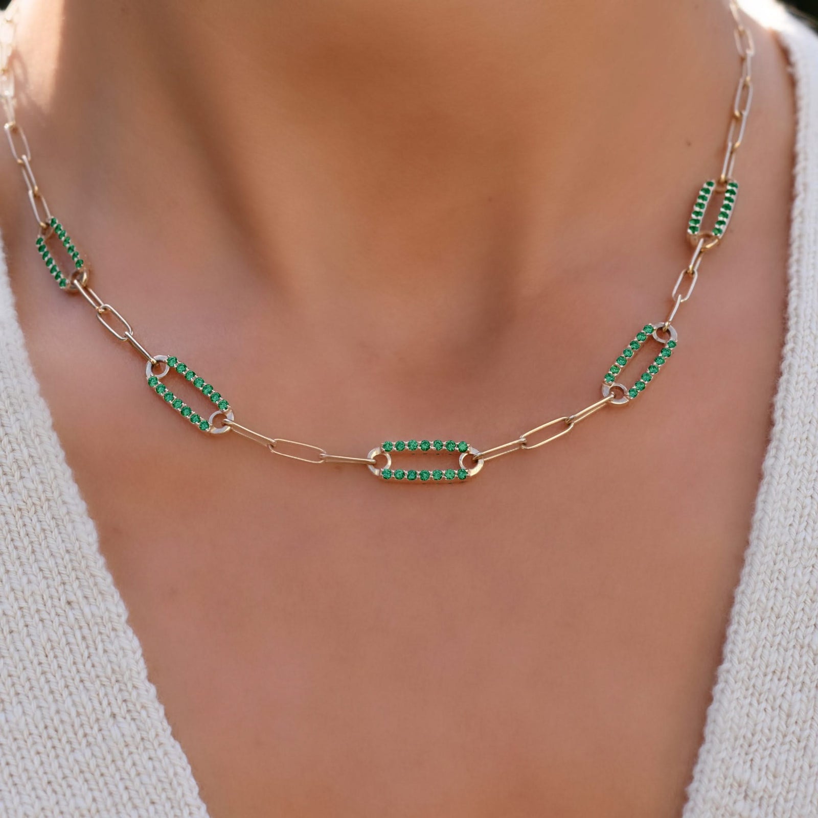Woman with a 14k gold Adelaide paperclip chain necklace featuring five links encrusted with 1.5 mm pavé emeralds