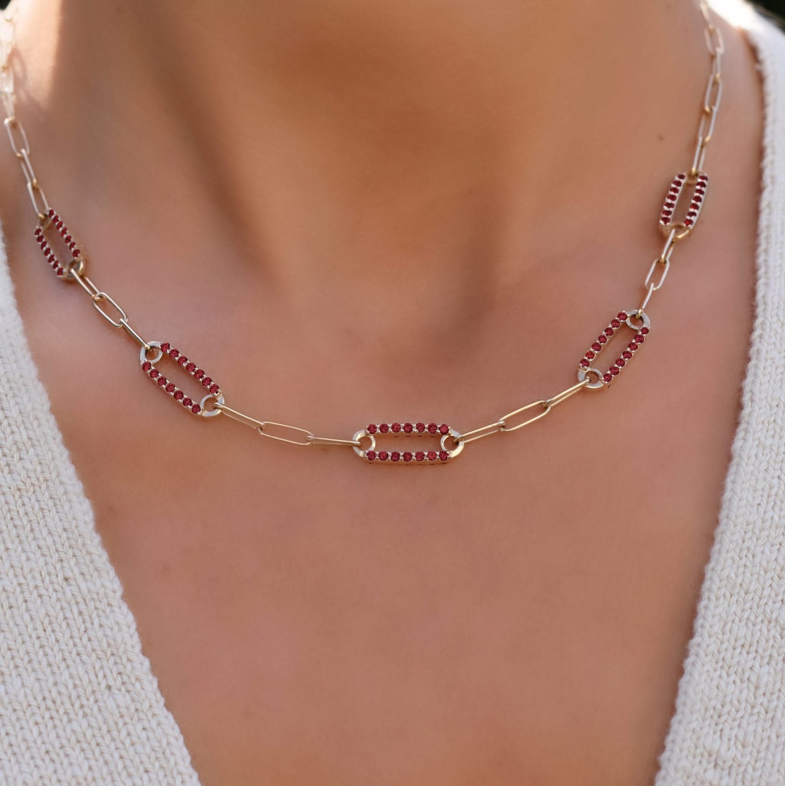 Woman with a 14k gold Adelaide paperclip chain necklace featuring five links encrusted with 1.5 mm pavé garnets