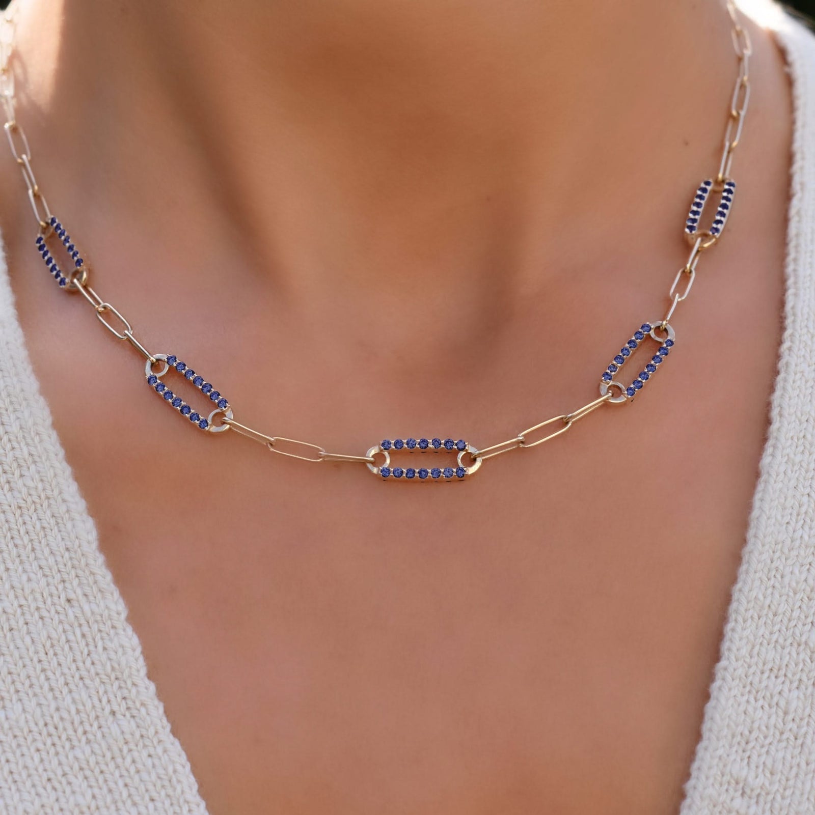 Woman with a 14k yellow gold Adelaide paperclip chain necklace featuring five links encrusted with 1.5 mm pavé sapphires