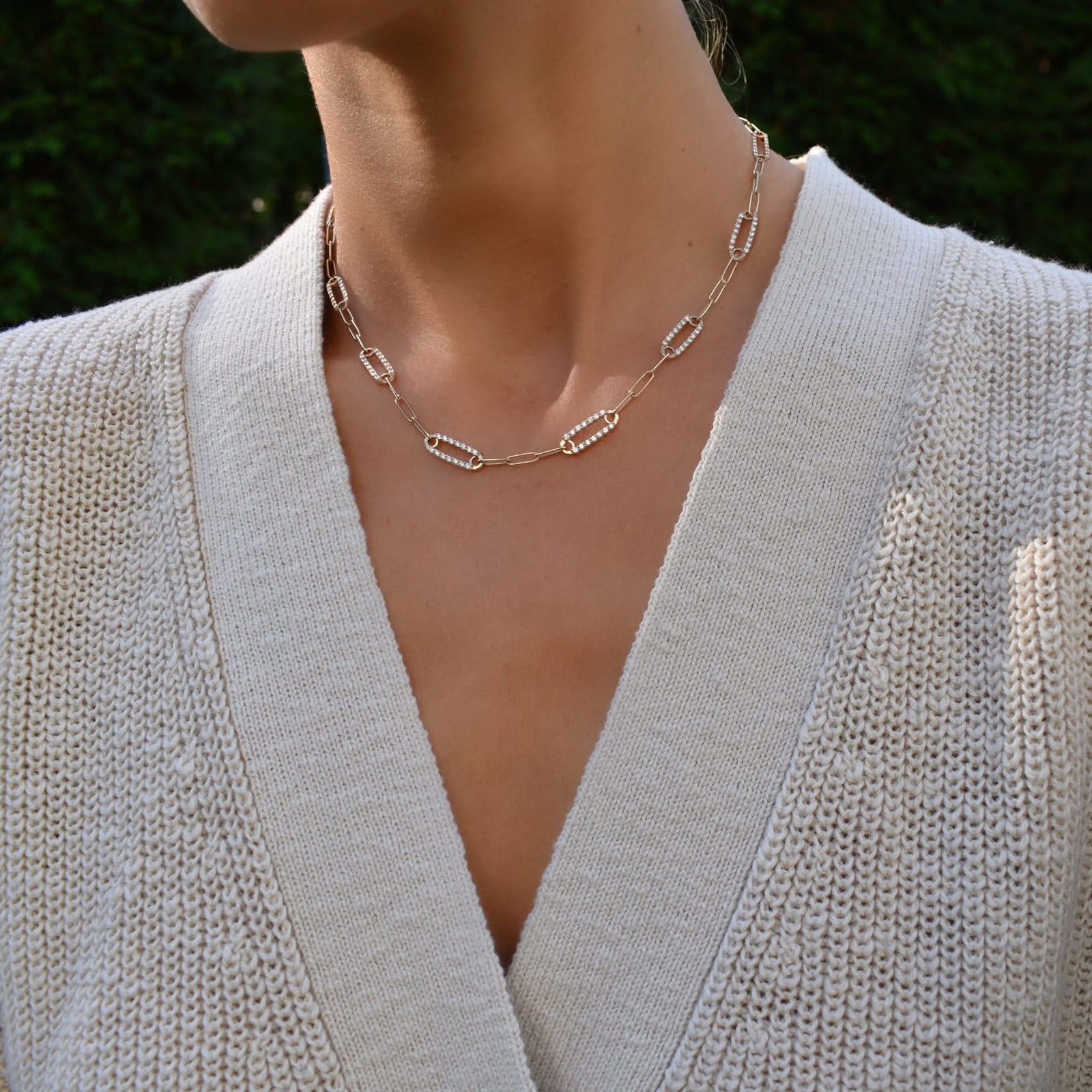 Woman wearing a 14k gold Adelaide paperclip chain pavé necklace featuring eight gemstone-encrusted links