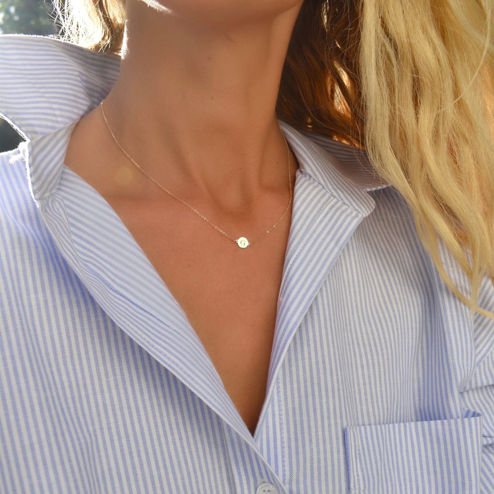Woman wearing a 14k yellow gold cable chain necklace featuring one 1/4” flat disc engraved with the letter G