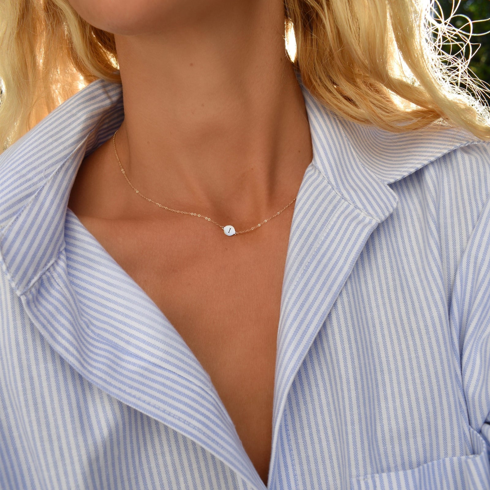 Woman wearing a 14k yellow gold cable chain necklace featuring one 1/4” flat disc engraved with the letter I