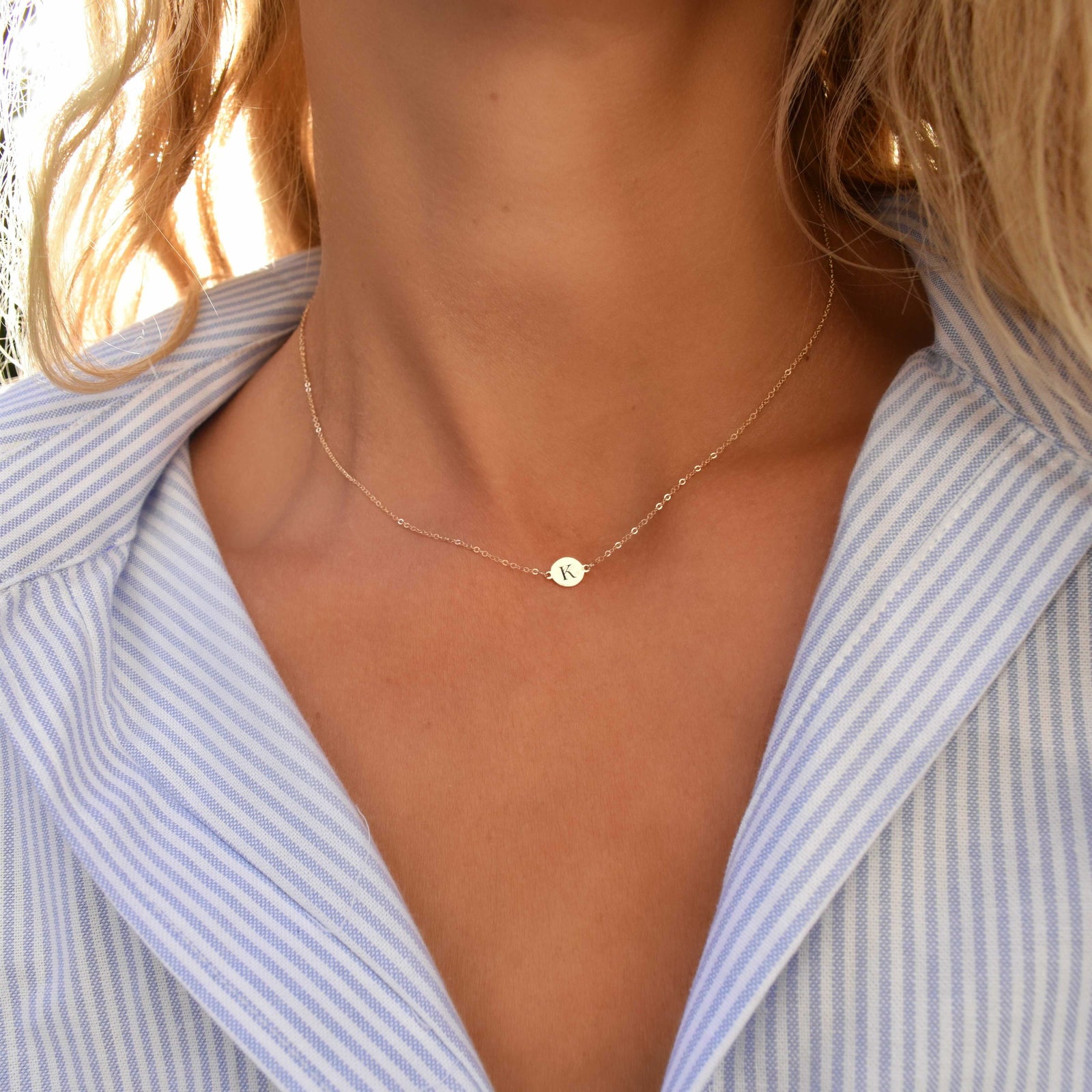Woman wearing a 14k yellow gold cable chain necklace featuring one 1/4” flat disc engraved with the letter K