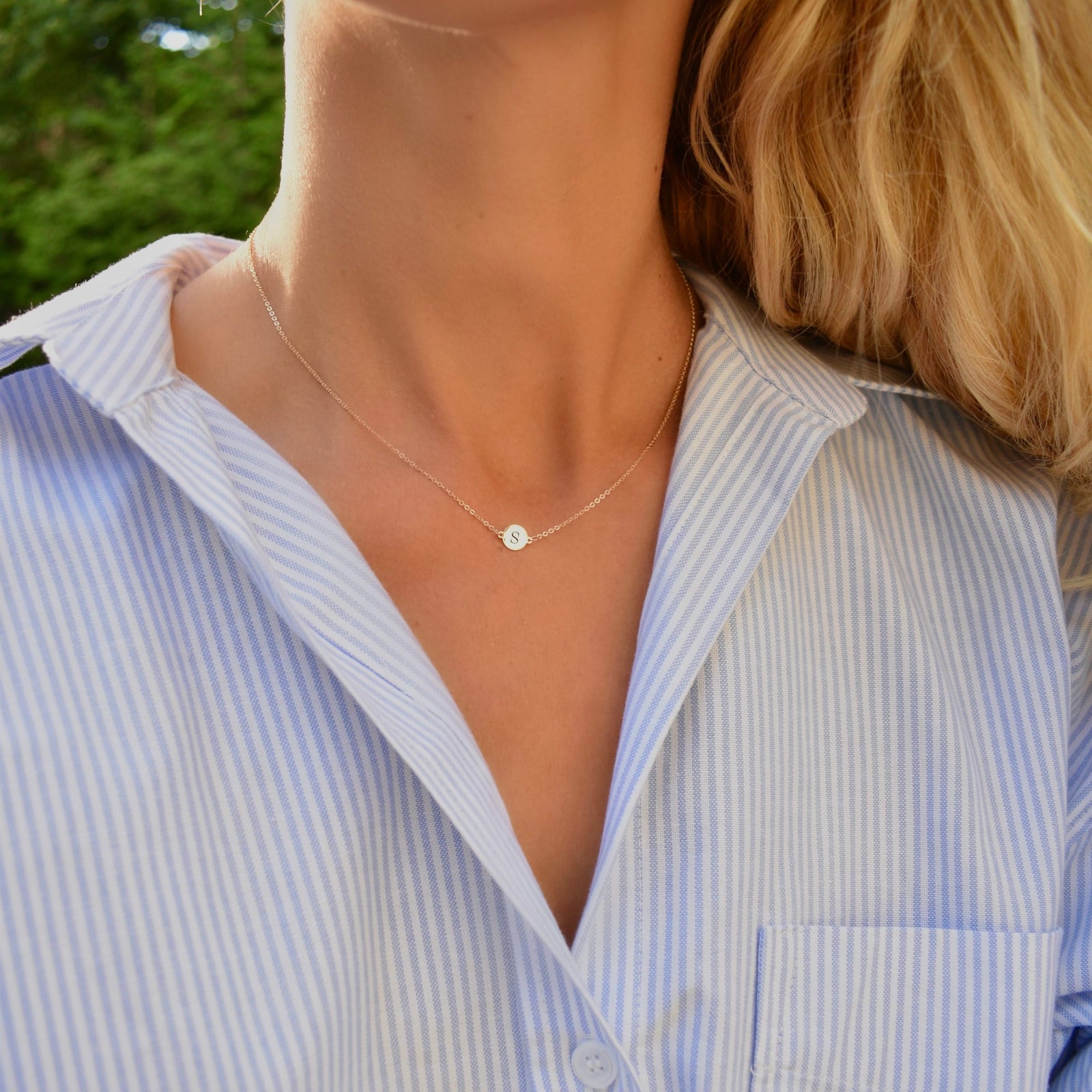 Woman wearing a 14k yellow gold cable chain necklace featuring one 1/4” flat disc engraved with the letter S