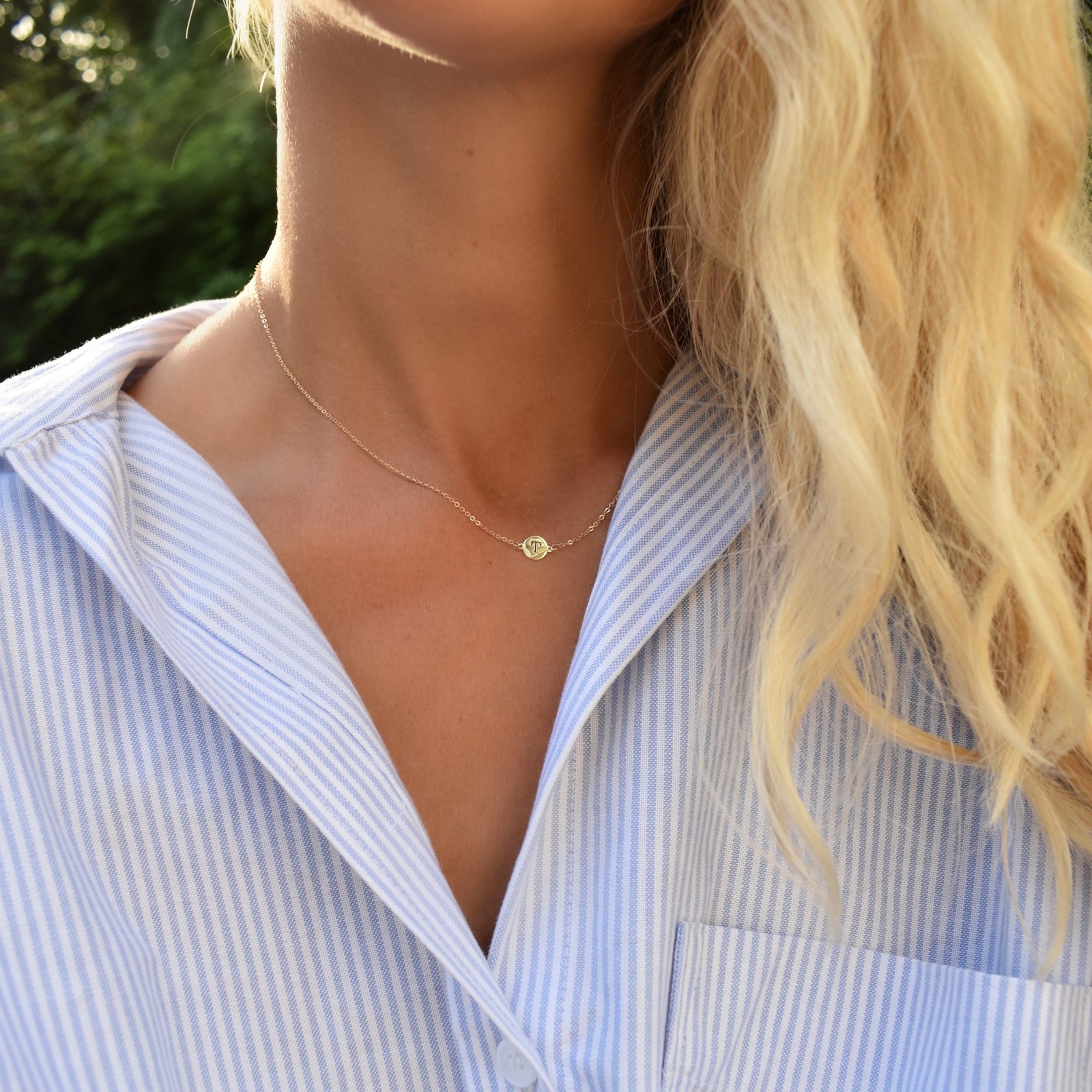Woman wearing a 14k yellow gold cable chain necklace featuring one 1/4” flat disc engraved with the letter T