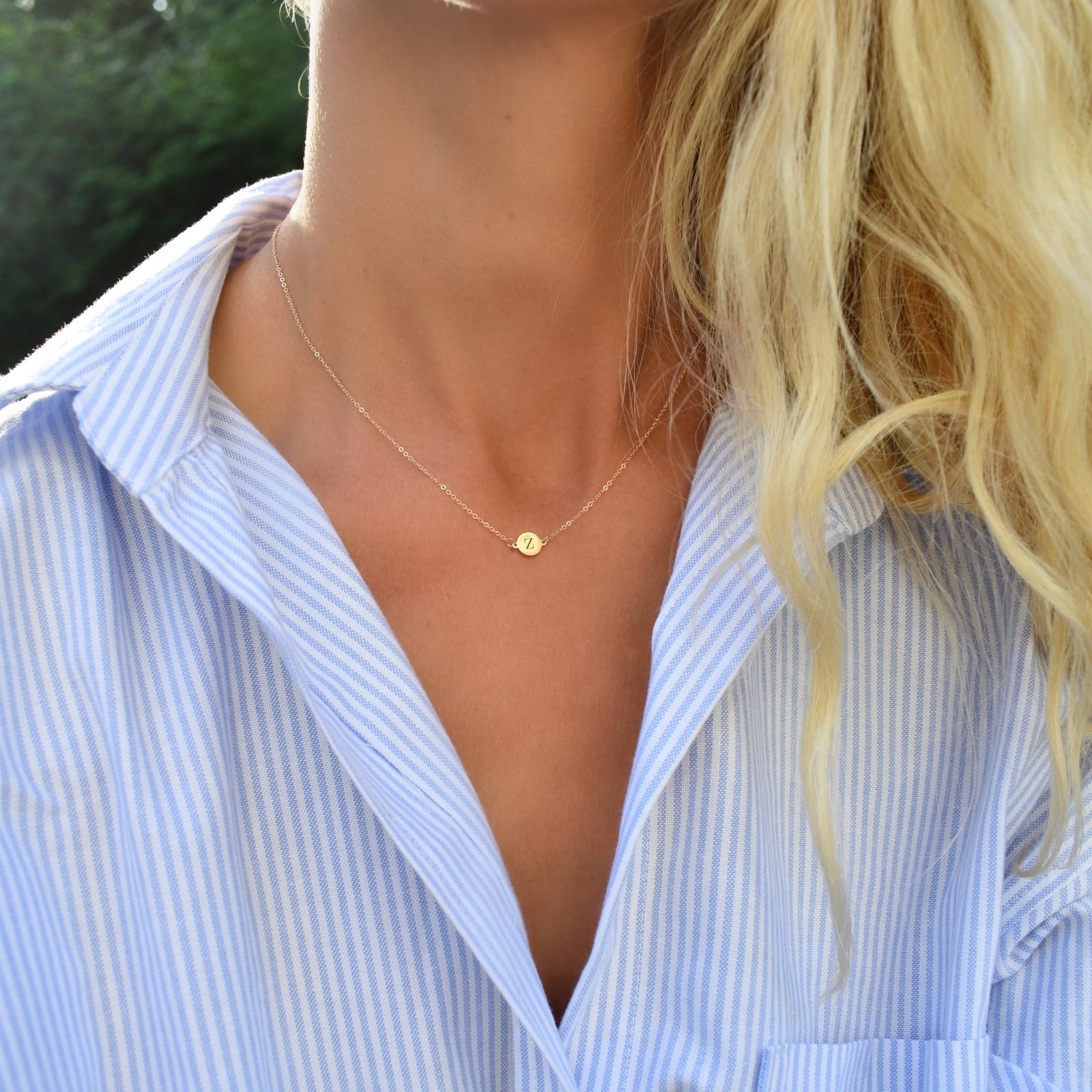 Woman wearing a 14k yellow gold cable chain necklace featuring one 1/4” flat disc engraved with the letter Z