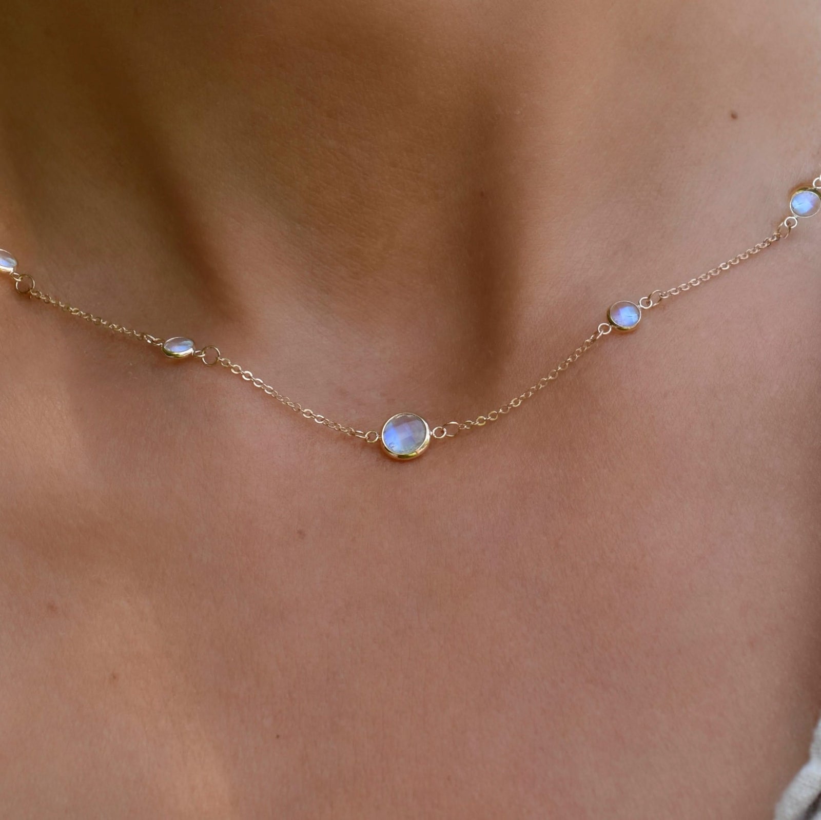 Woman wearing a Grand & Classic necklace featuring one 6 mm and four 4 mm Moonstones bezel set in 14k yellow gold