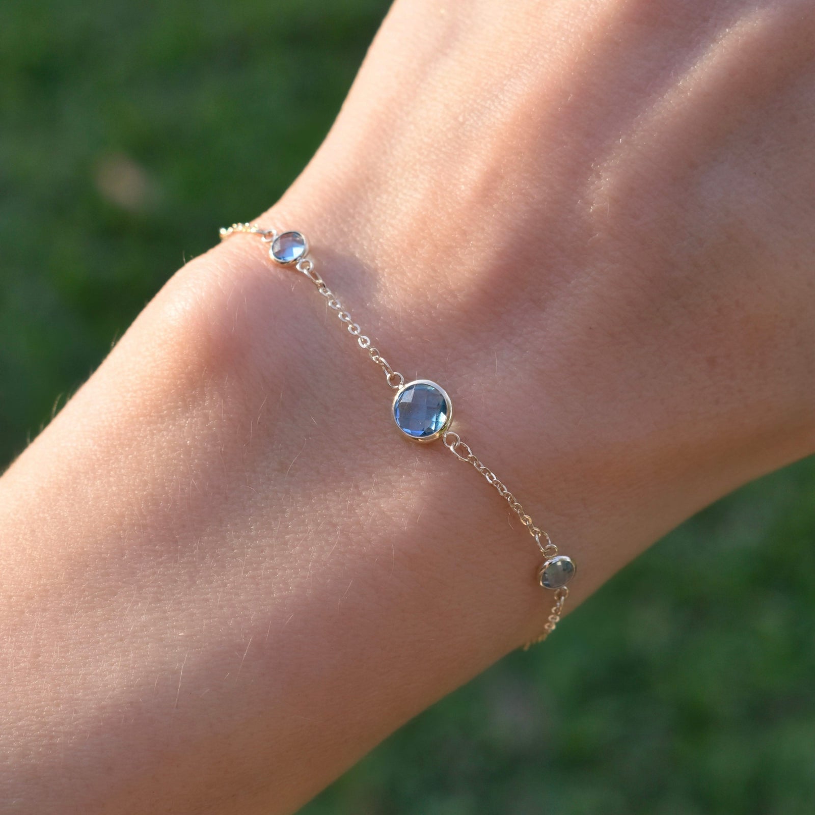 Woman with a Grand & Classic bracelet featuring one 6 mm and four 4 mm briolette Nantucket Blue Topaz bezel set in 14k gold