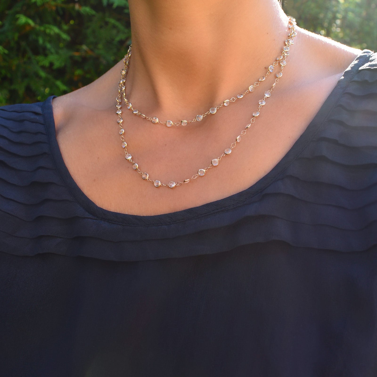 Woman with a Newport Wrap necklace featuring 4 mm briolette cut white topaz bezel set in 14k yellow gold