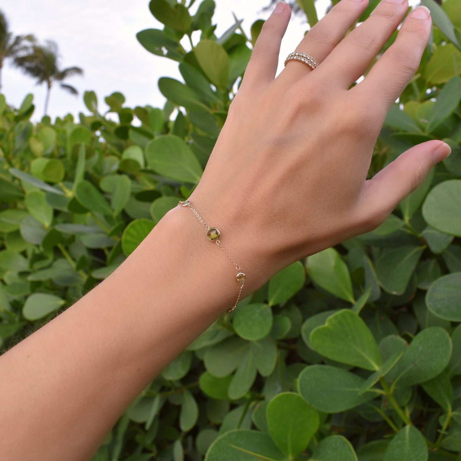 Woman wearing a Grand & Classic bracelet featuring one 6 mm and four 4 mm briolette Peridots bezel set in 14k yellow gold