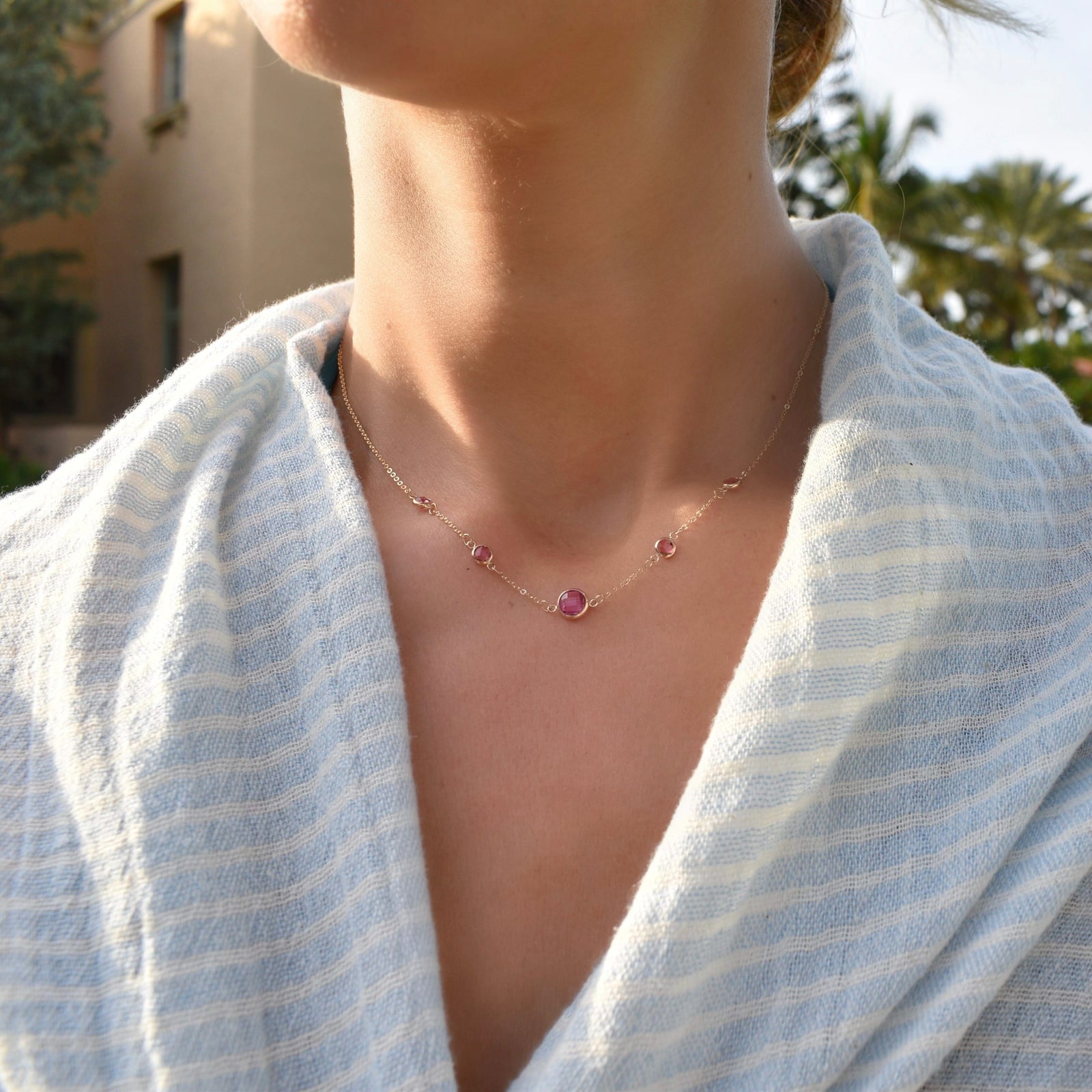 Woman with a Grand & Classic necklace featuring one 6 mm Pink Sapphire and four 4 mm Pink Tourmalines bezel set in 14k gold