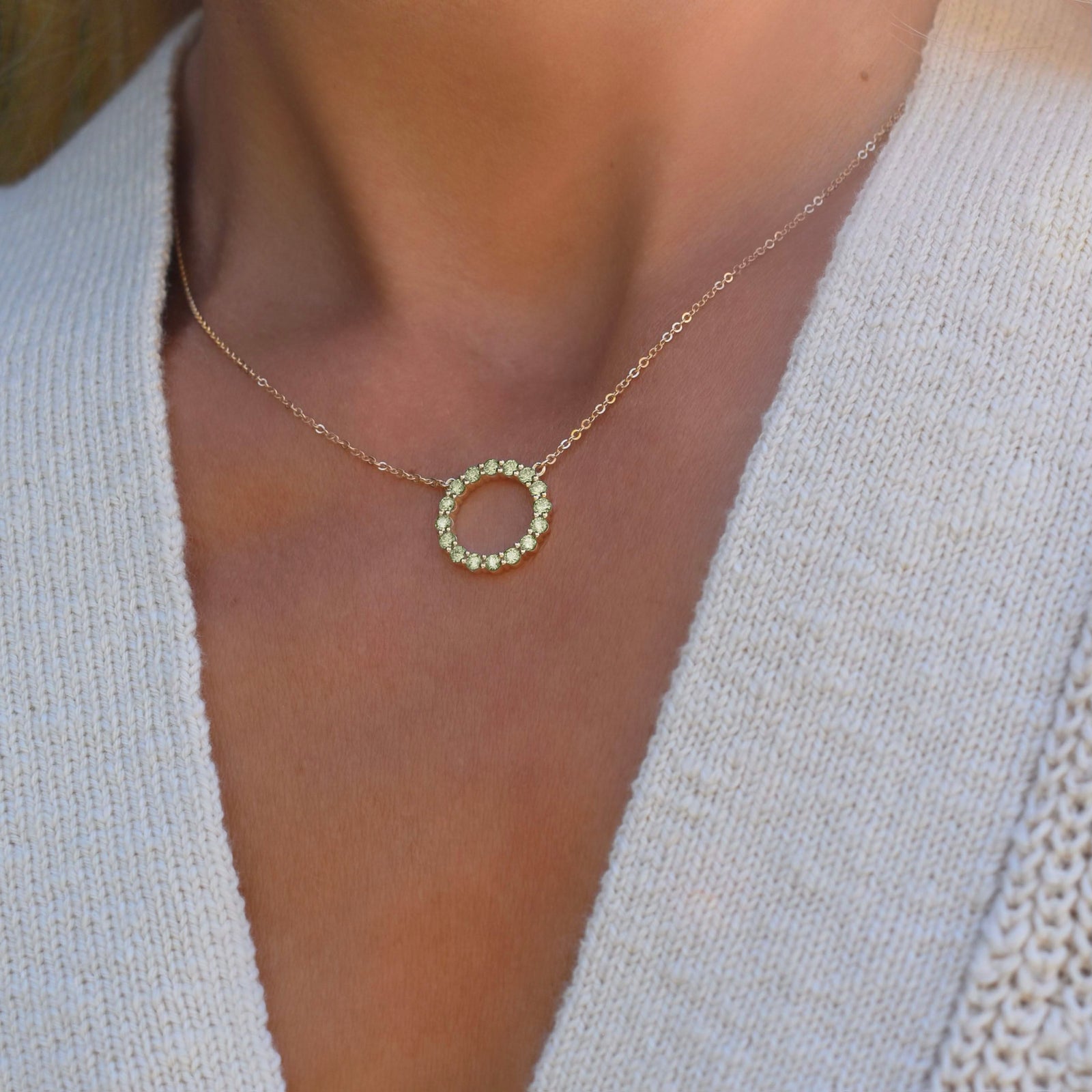 Woman wearing a Rosecliff open circle necklace with sixteen 2 mm faceted round cut peridots prong set in 14k gold