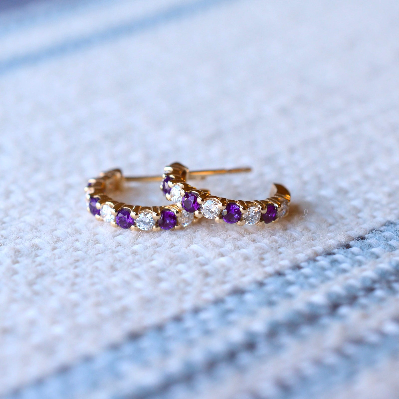 Pair of Rosecliff huggie earrings in 14k gold each featuring nine alternating 2mm round cut amethysts and diamonds
