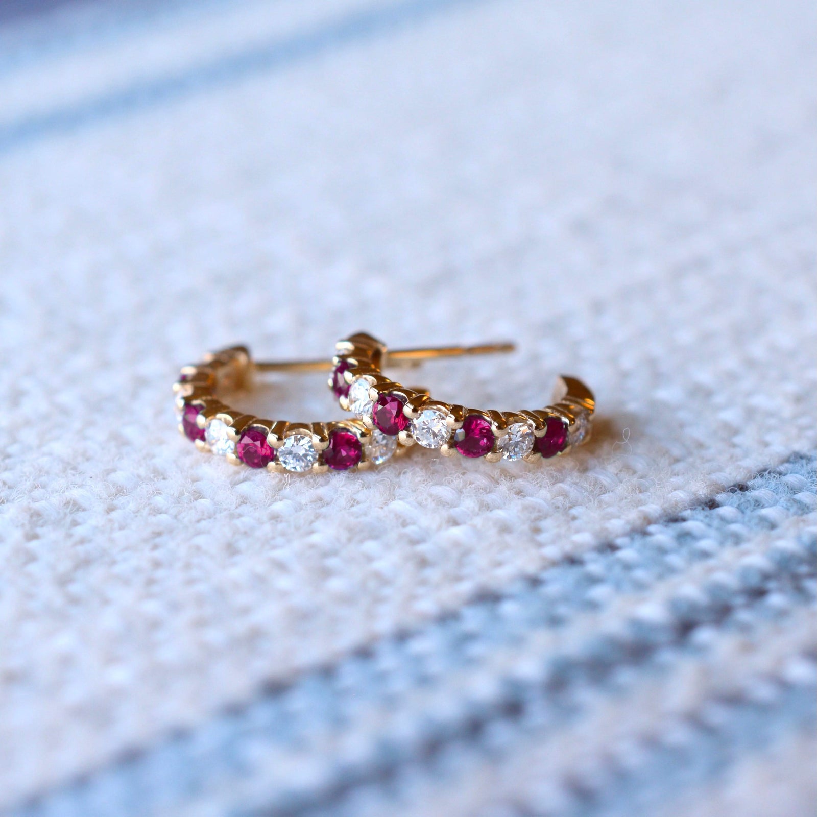 Pair of Rosecliff huggie earrings in 14k gold each featuring nine alternating 2 mm round cut rubies and diamonds