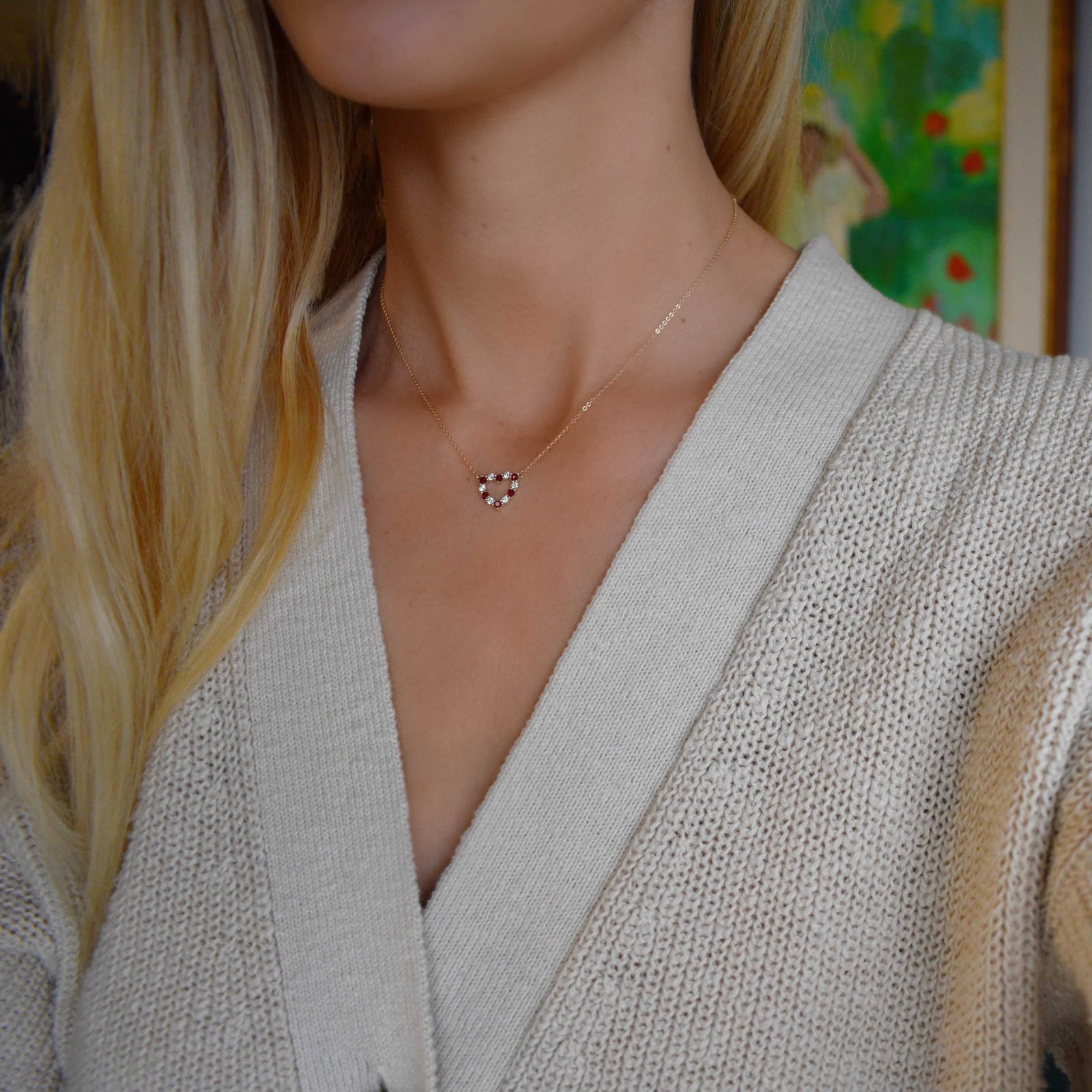 Woman with a Rosecliff Heart Necklace featuring twelve alternating garnets and diamonds prong set in 14k yellow Gold
