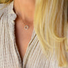 Woman wearing a Rosecliff small open circle necklace with twelve 2 mm faceted round cut diamonds prong set in 14k gold