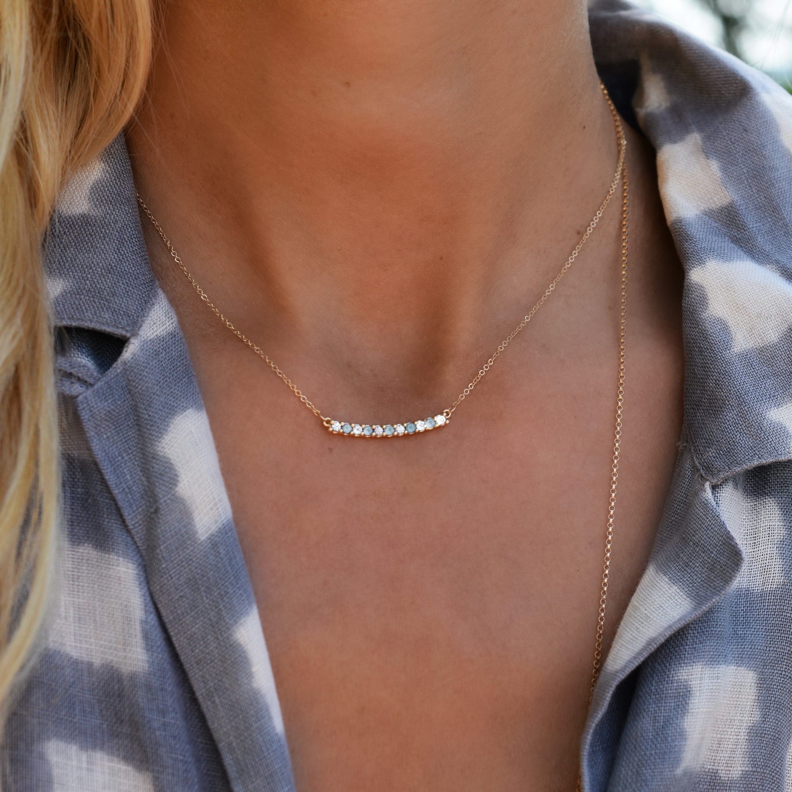 Woman with a Rosecliff bar necklace with eleven alternating 2 mm Nantucket blue topaz and diamonds prong set in 14k gold