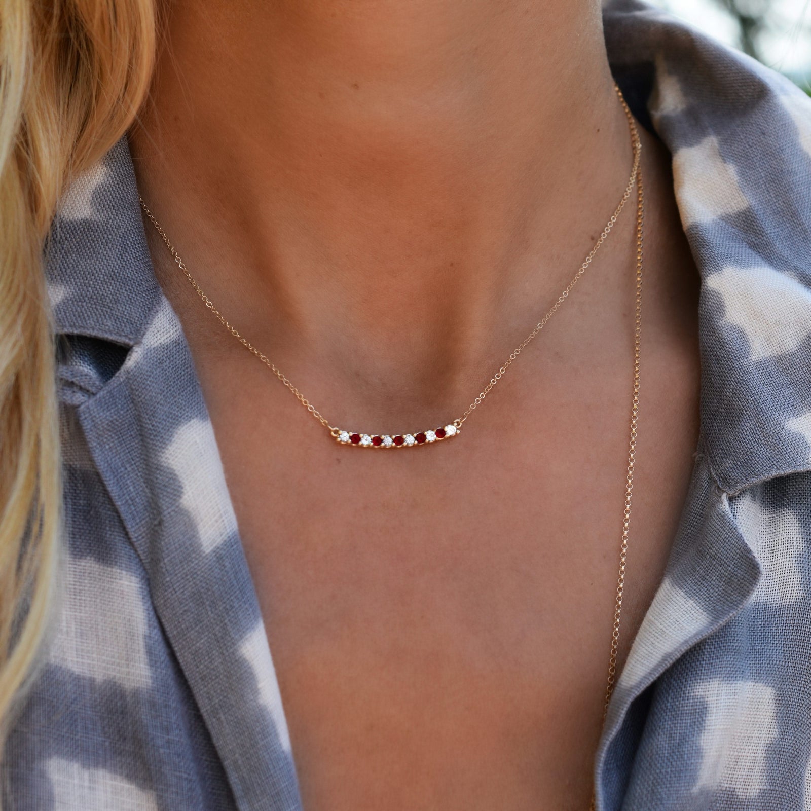 Woman wearing a Rosecliff bar necklace with eleven alternating 2 mm round cut garnets and diamonds prong set in 14k gold