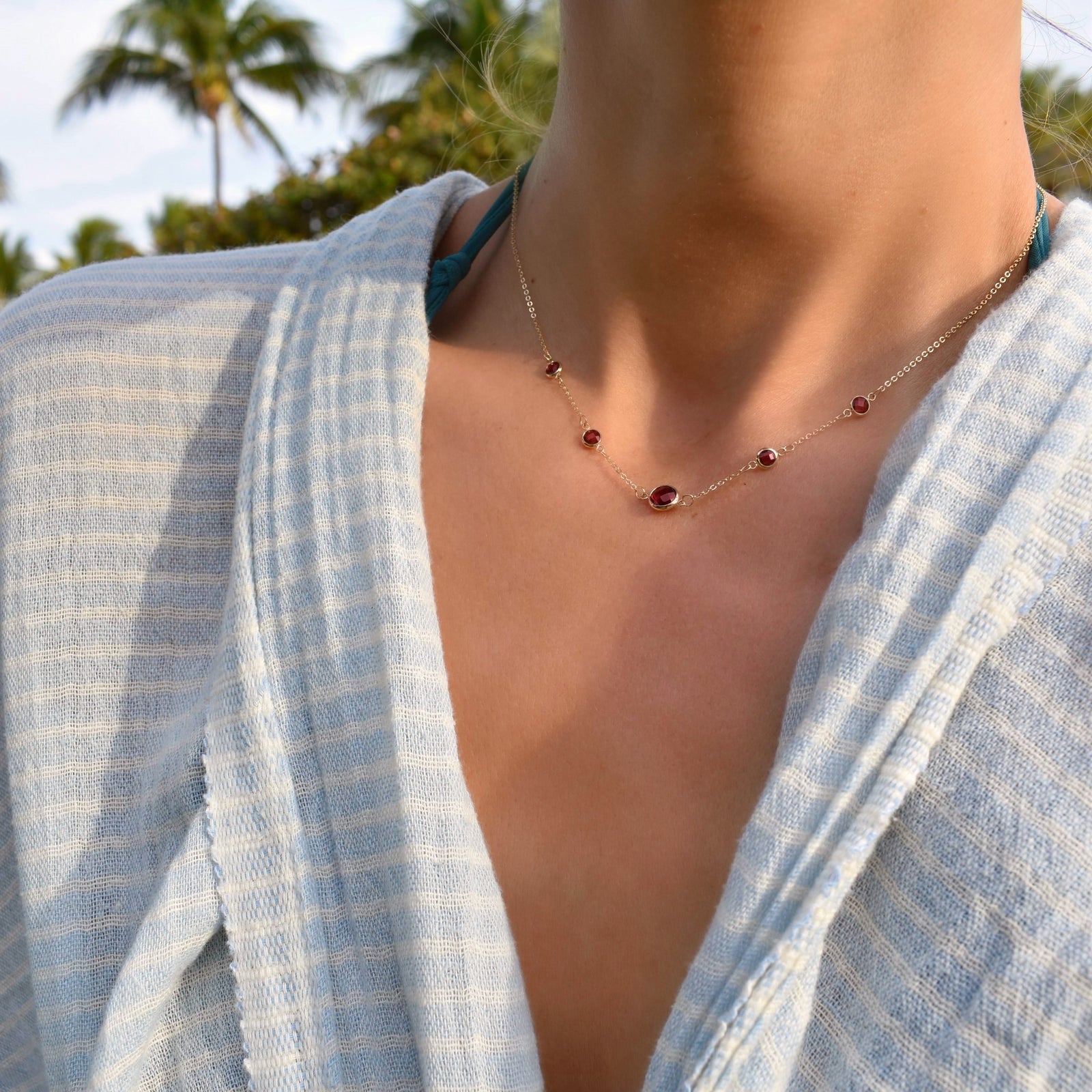 Woman wearing a Grand & Classic necklace featuring one 6 mm and four 4 mm Rubies bezel set in 14k yellow gold