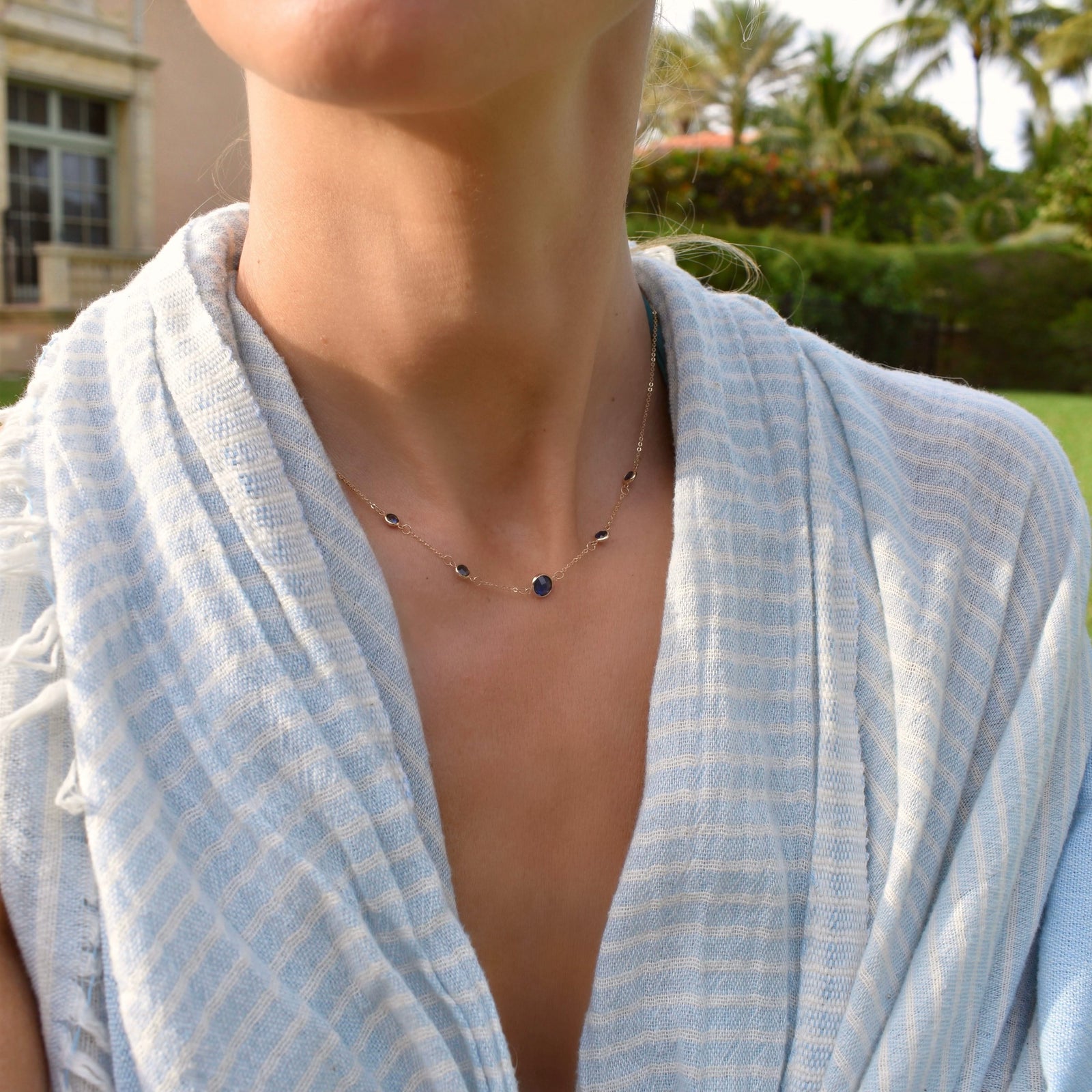 Woman wearing a Grand & Classic necklace featuring one 6 mm and four 4 mm Sapphires bezel set in 14k yellow gold