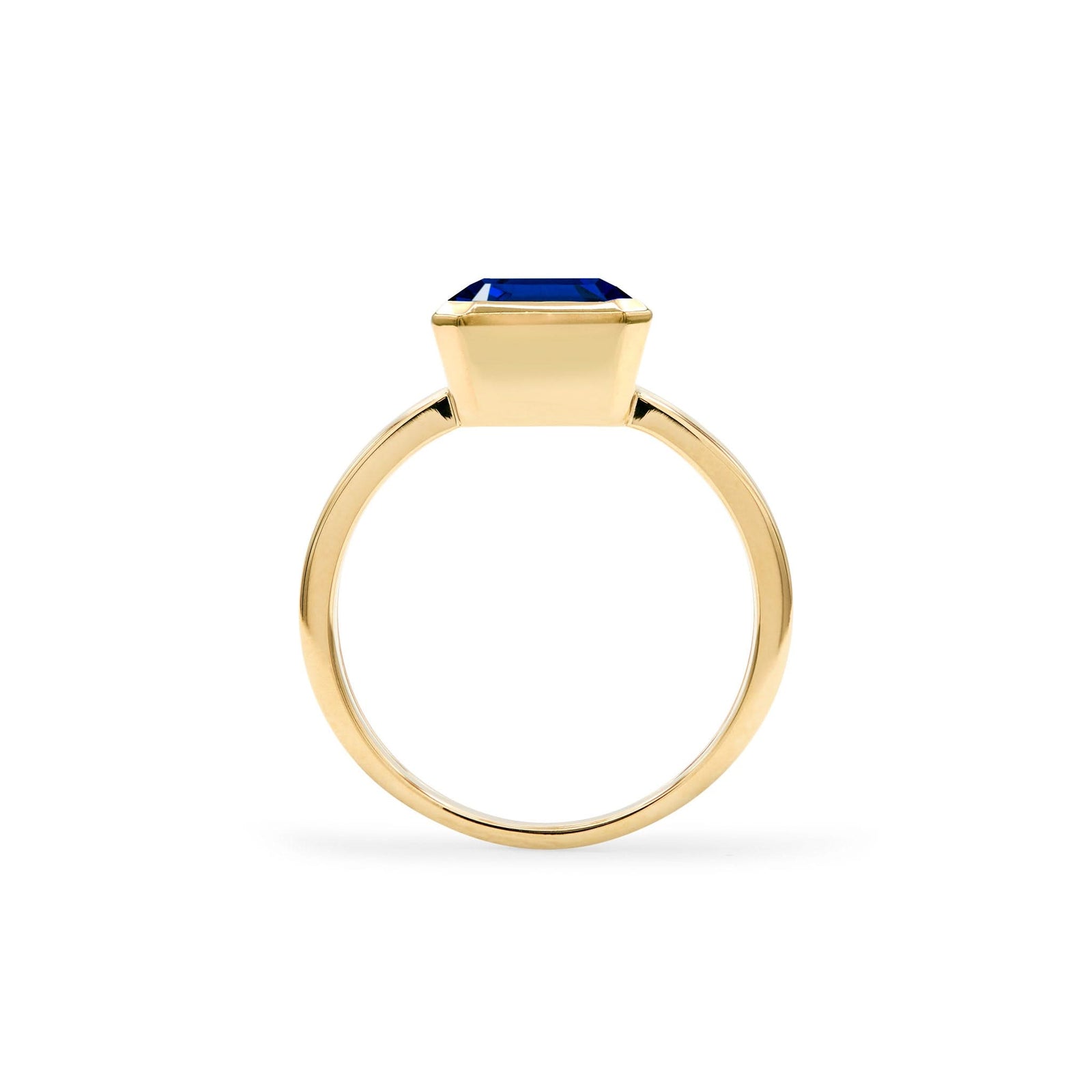 Warren ring in 14k yellow gold featuring one 10 x 8 mm emerald cut bezel set sapphire - standing view