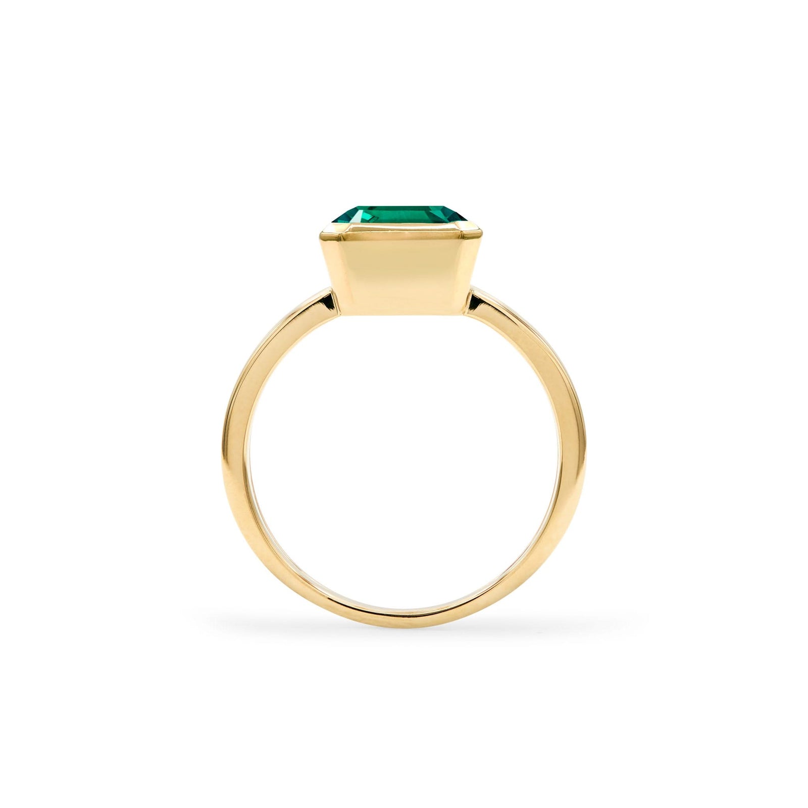 Warren ring in 14k yellow gold featuring one 10 x 8 mm emerald cut bezel set emerald - standing view