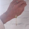 Woman holding an Adelaide paper clip chain with a Warren emerald cut bezel set lemon verbena quartz pendant in 14k gold