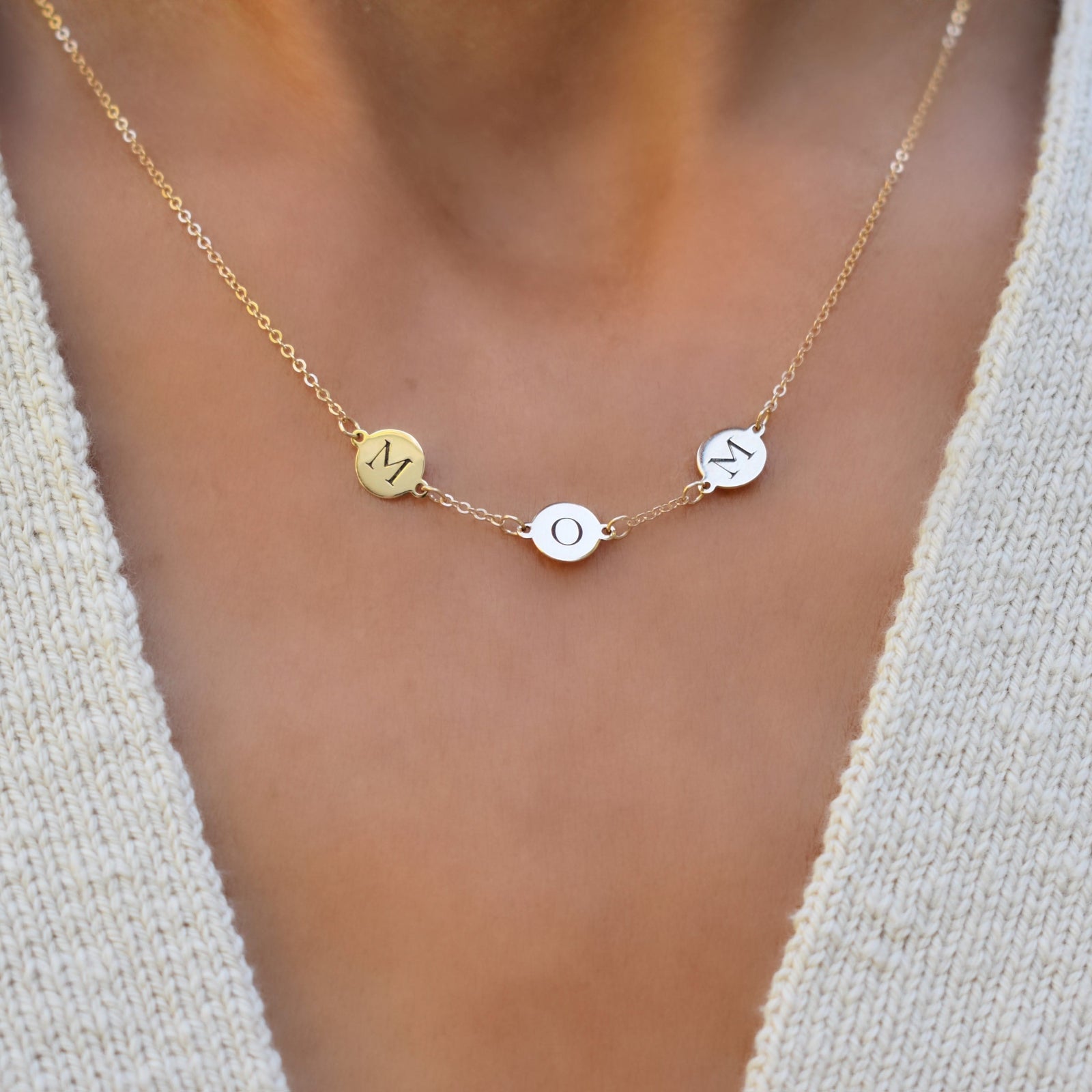 Woman wearing a 14k yellow gold cable chain necklace featuring three 1/4” flat engraved letter discs, spelling Mom
