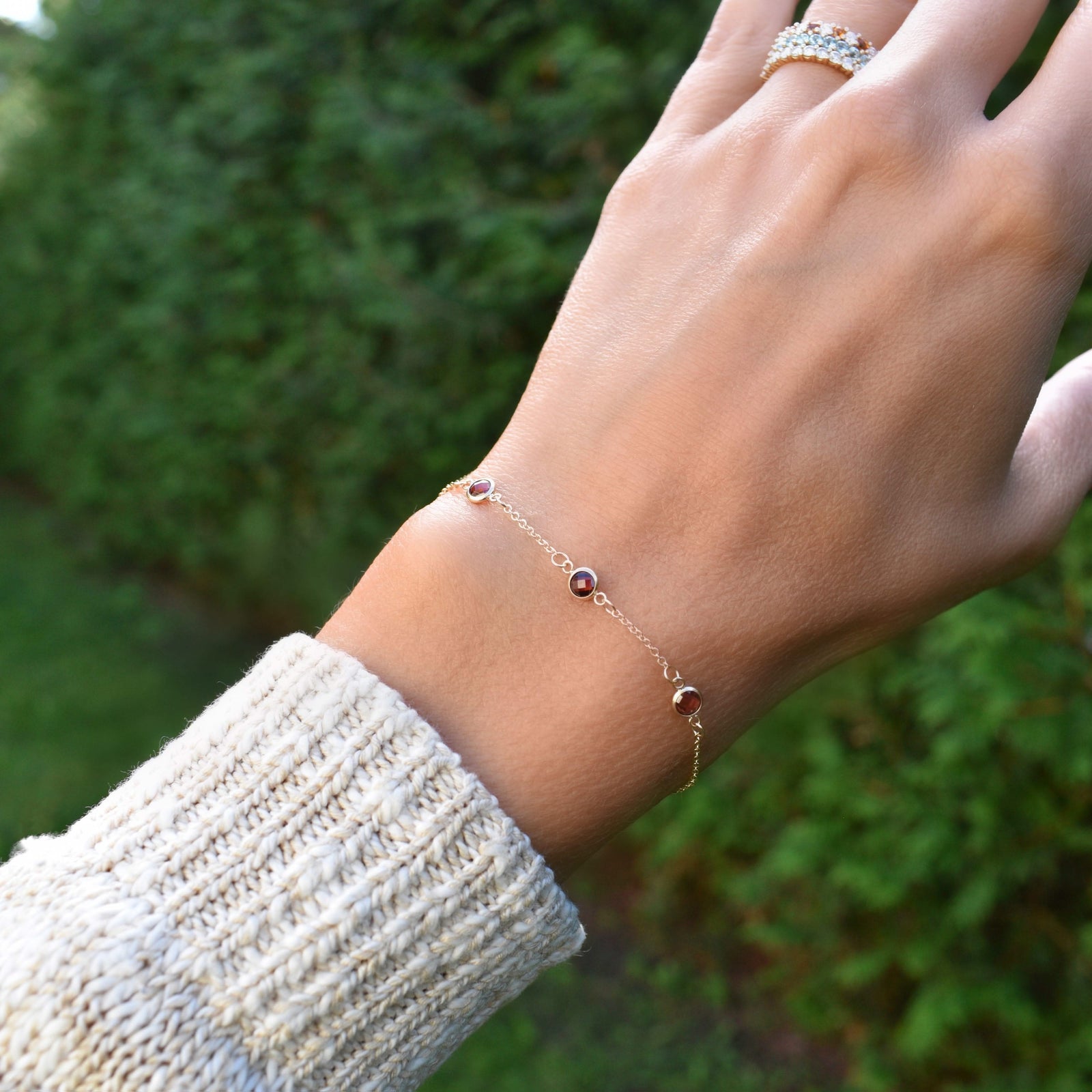 Woman with a Bayberry cable chain birthstone bracelet featuring three 4 mm briolette garnets bezel set in 14k yellow gold
