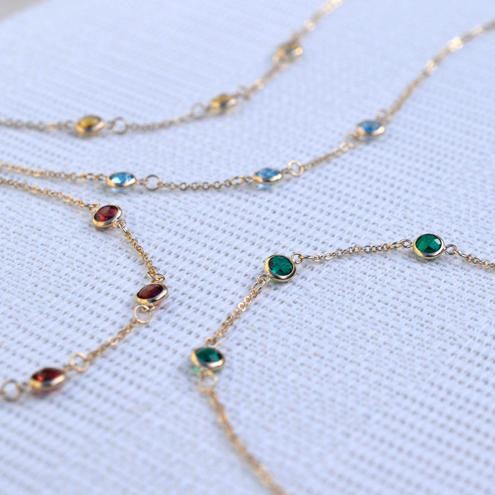 Multiple Bayberry cable chain birthstone bracelets each featuring three 4 mm briolette gemstones bezel set in 14k yellow gold