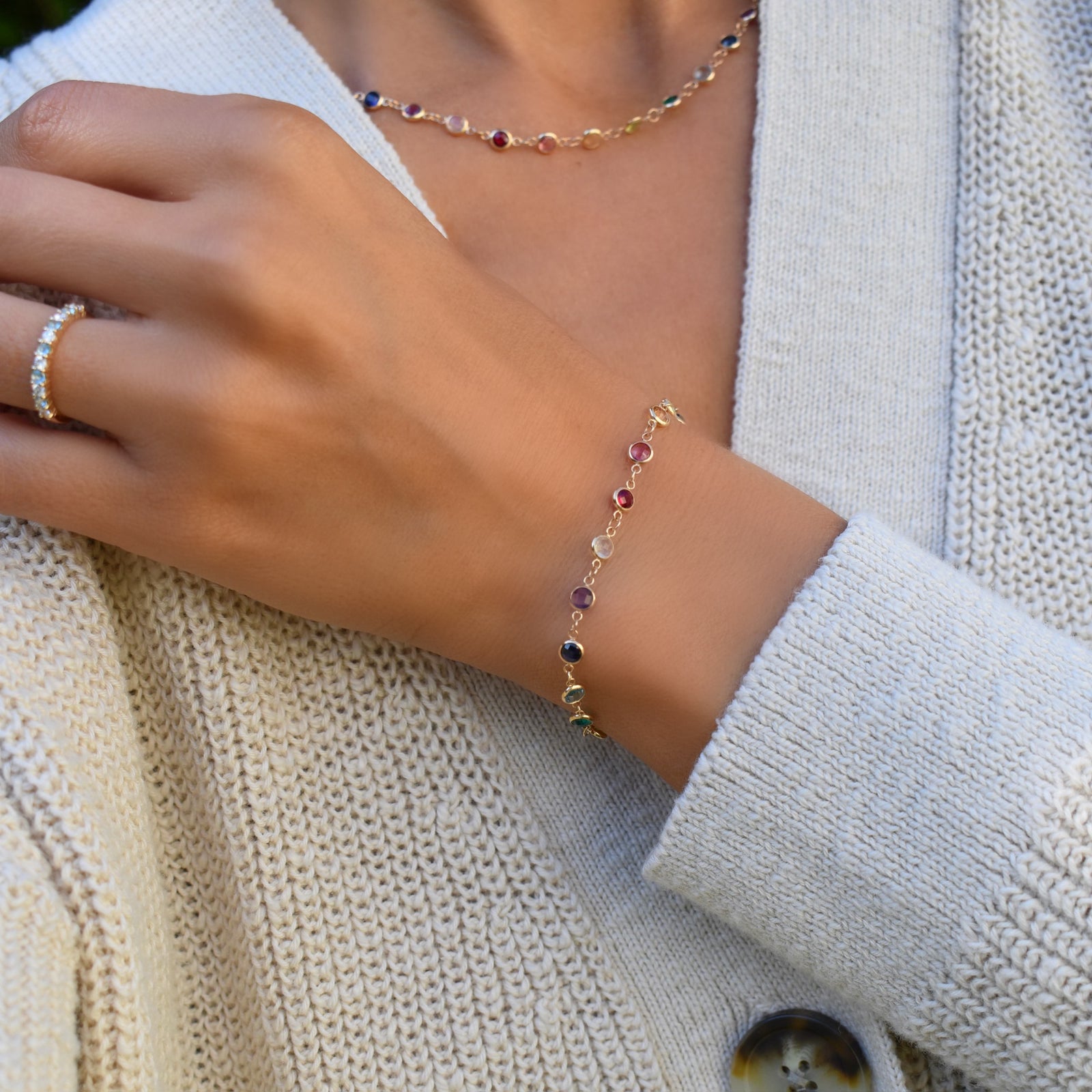 Woman wearing a Newport 14k yellow gold bracelet featuring 4 mm briolette cut bezel set rainbow hued gemstones