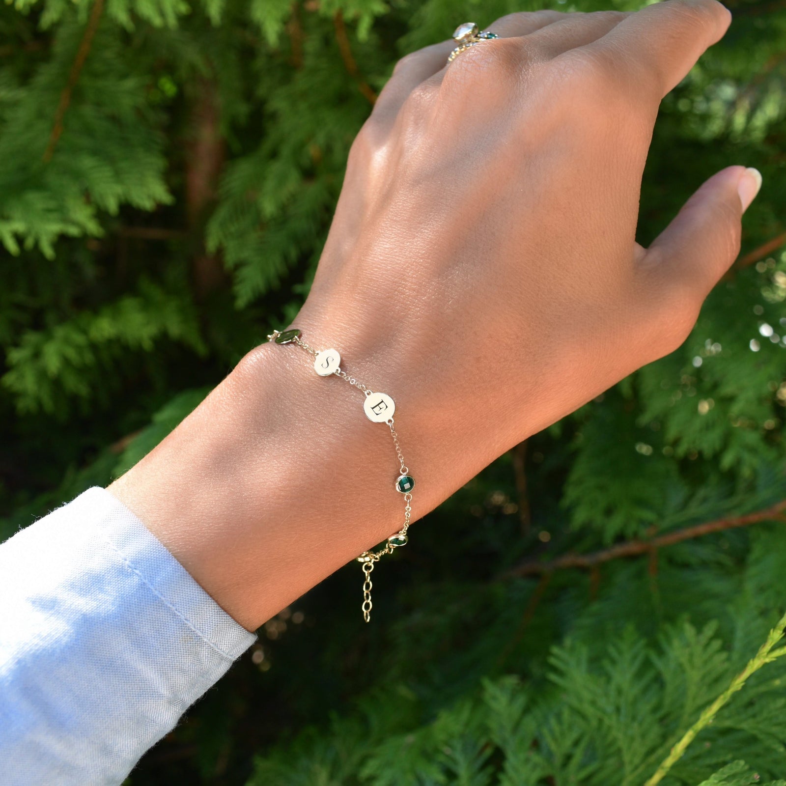 Woman wearing a 14k yellow gold Classic bracelet featuring birthstones and 1/4” flat letter-engraved discs