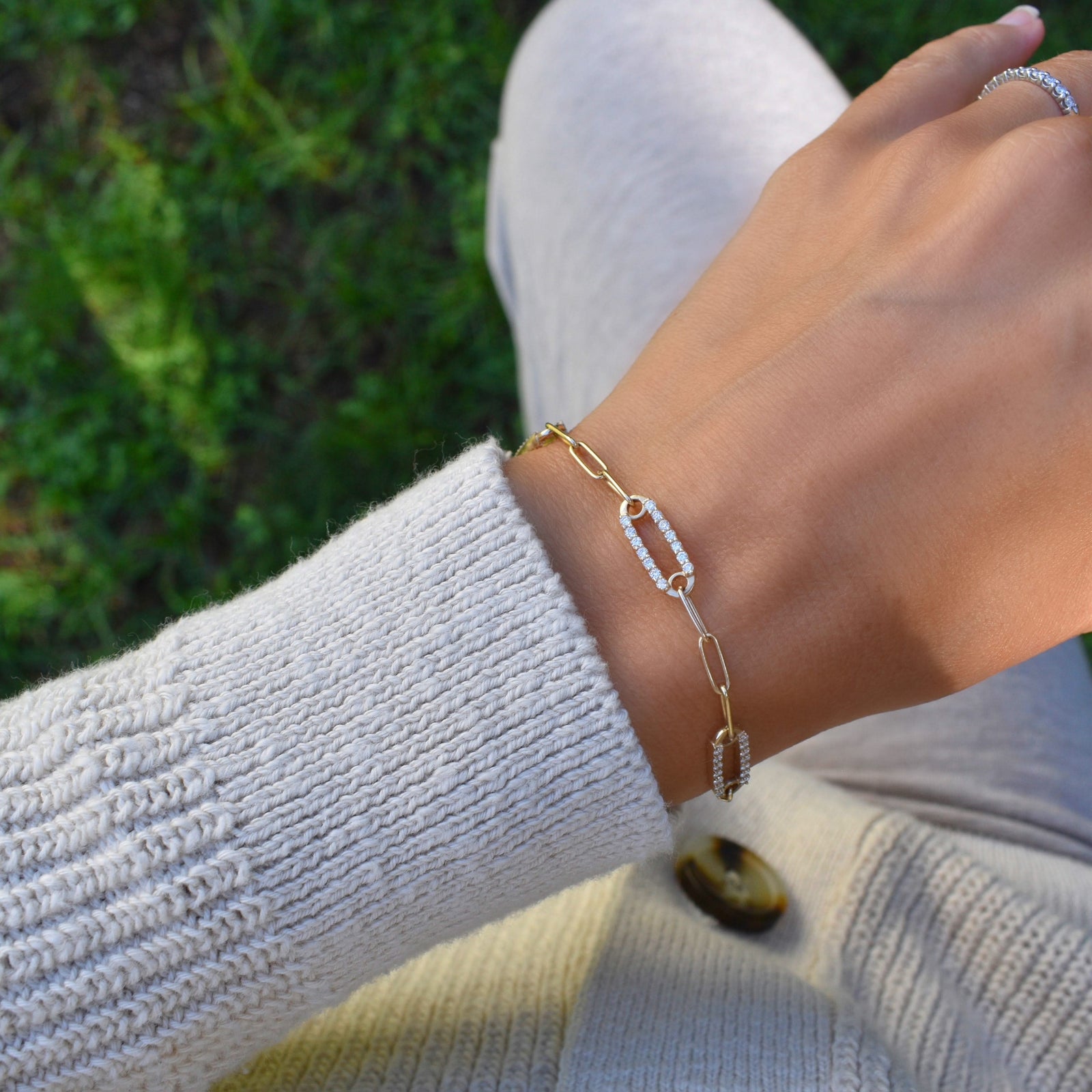 Woman wearing a 14k gold Adelaide paperclip chain pavé bracelet featuring gemstone-encrusted links