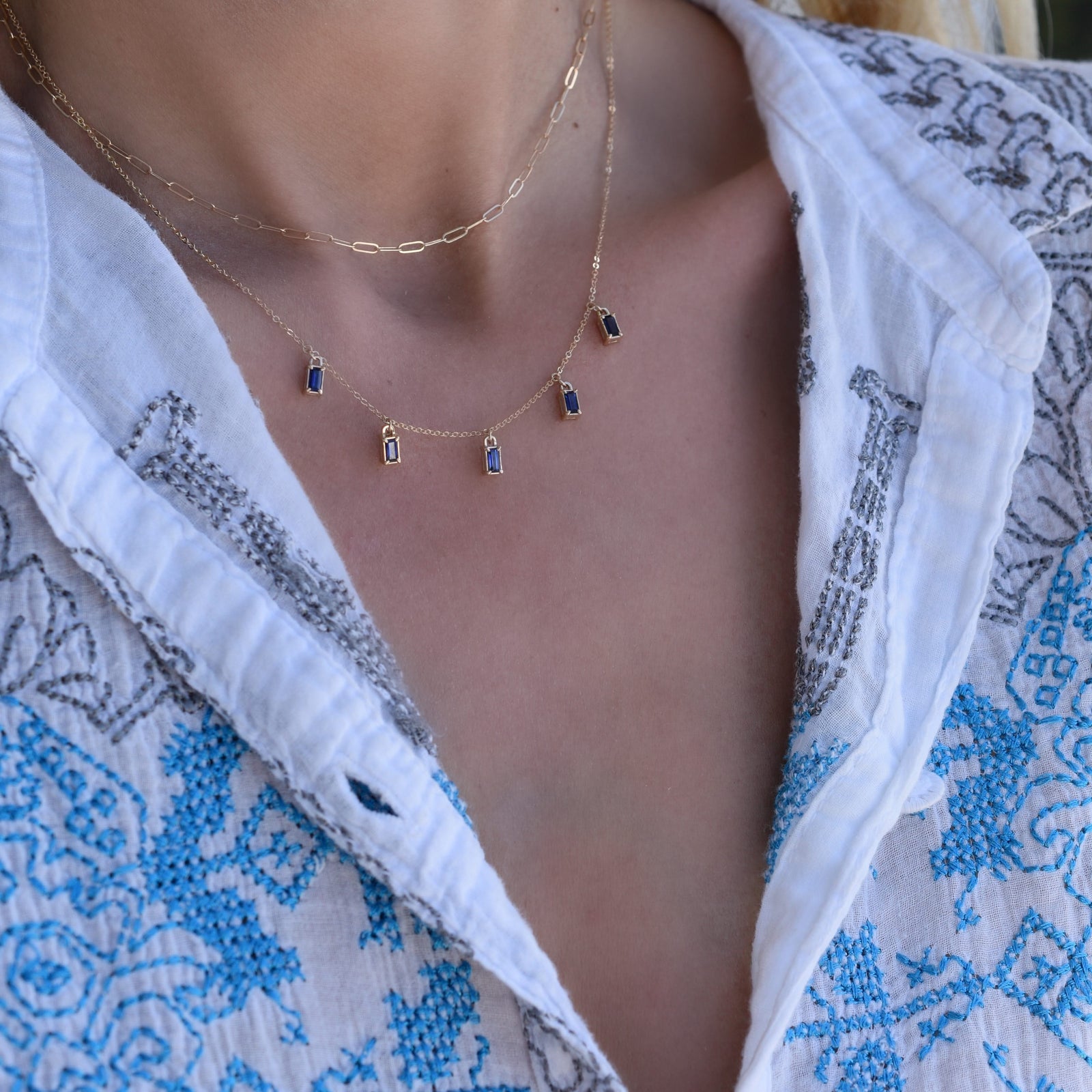 Woman wearing a Providence 5 Sapphire drop necklace with petite baguette cut stones set in 14k yellow gold