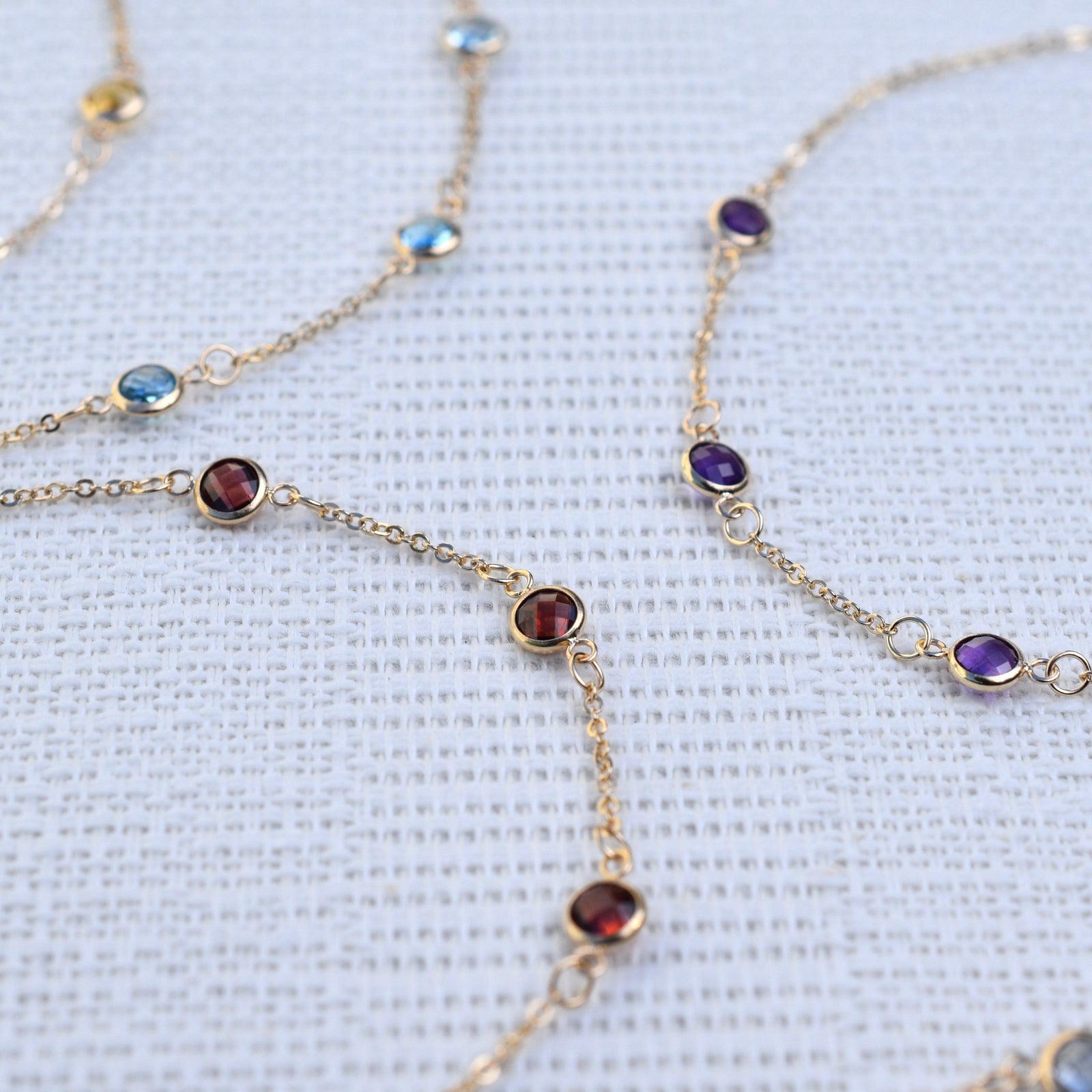 Multiple Bayberry cable chain birthstone bracelets each featuring three 4 mm briolette gemstones bezel set in 14k yellow gold