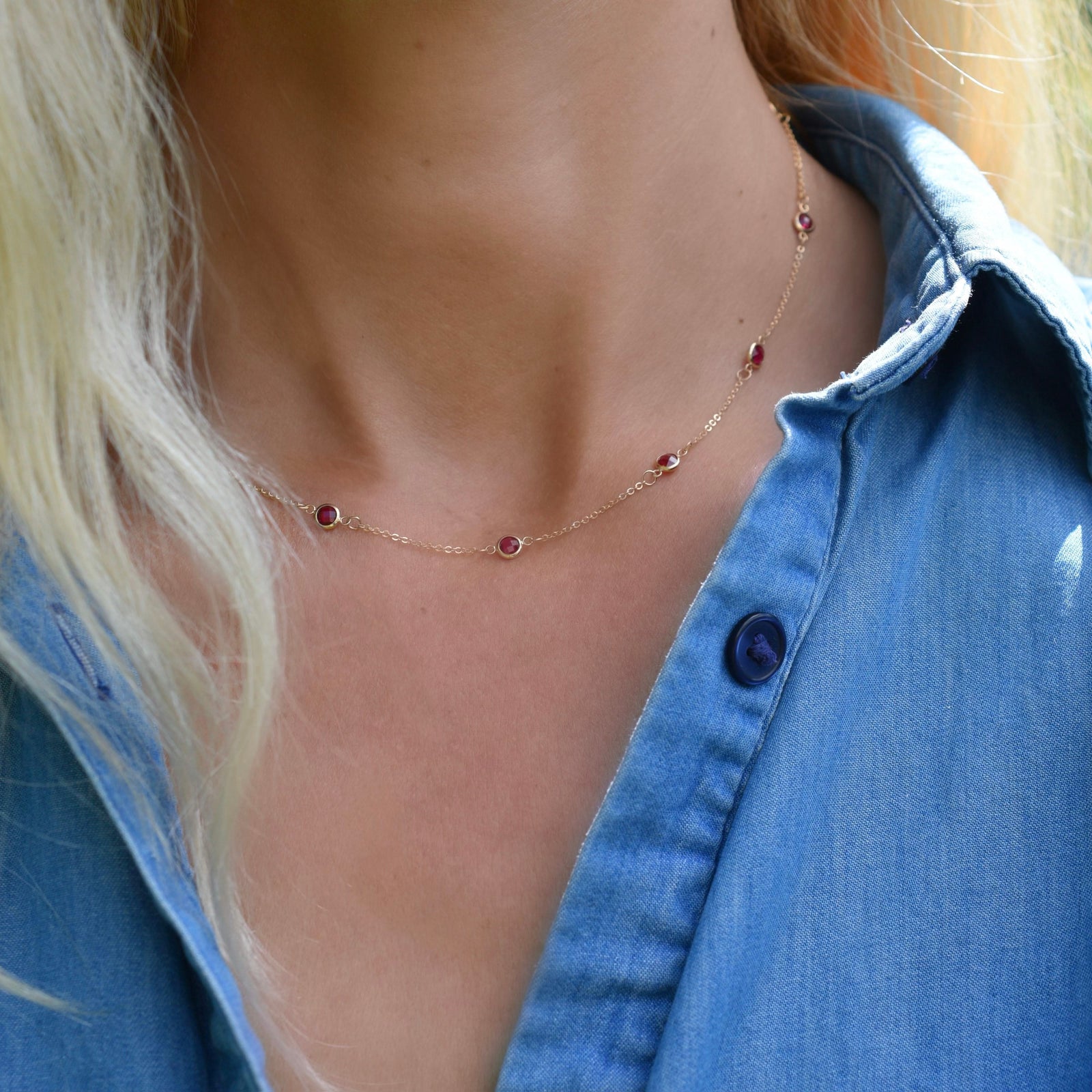 Woman wearing a Bayberry 11 Birthstone necklace featuring 4 mm briolette rubies bezel set in 14k gold