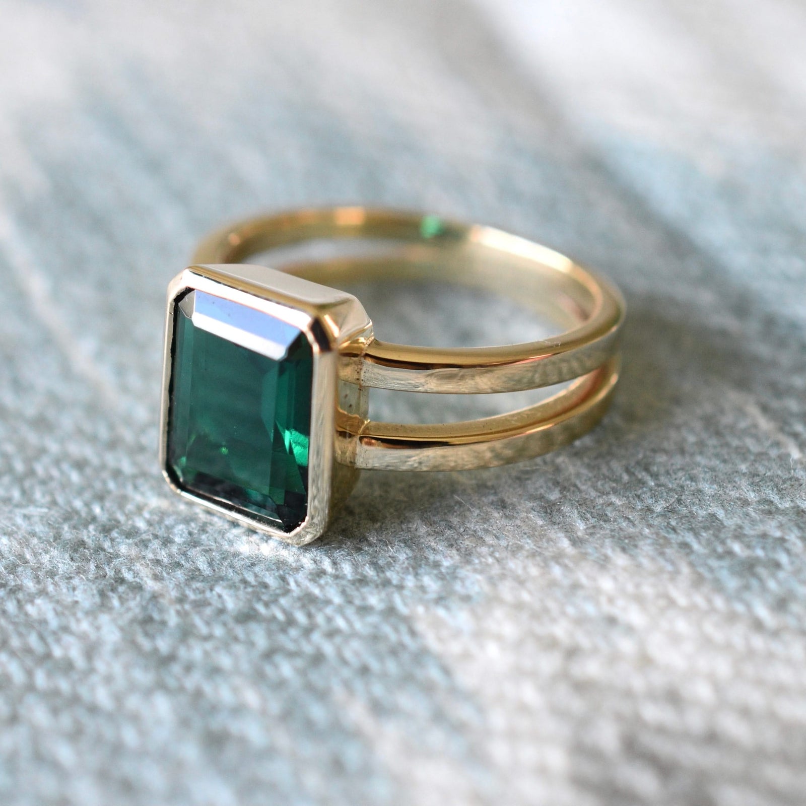 Warren ring in 14k yellow gold featuring one 10 x 8 mm emerald cut bezel set emerald